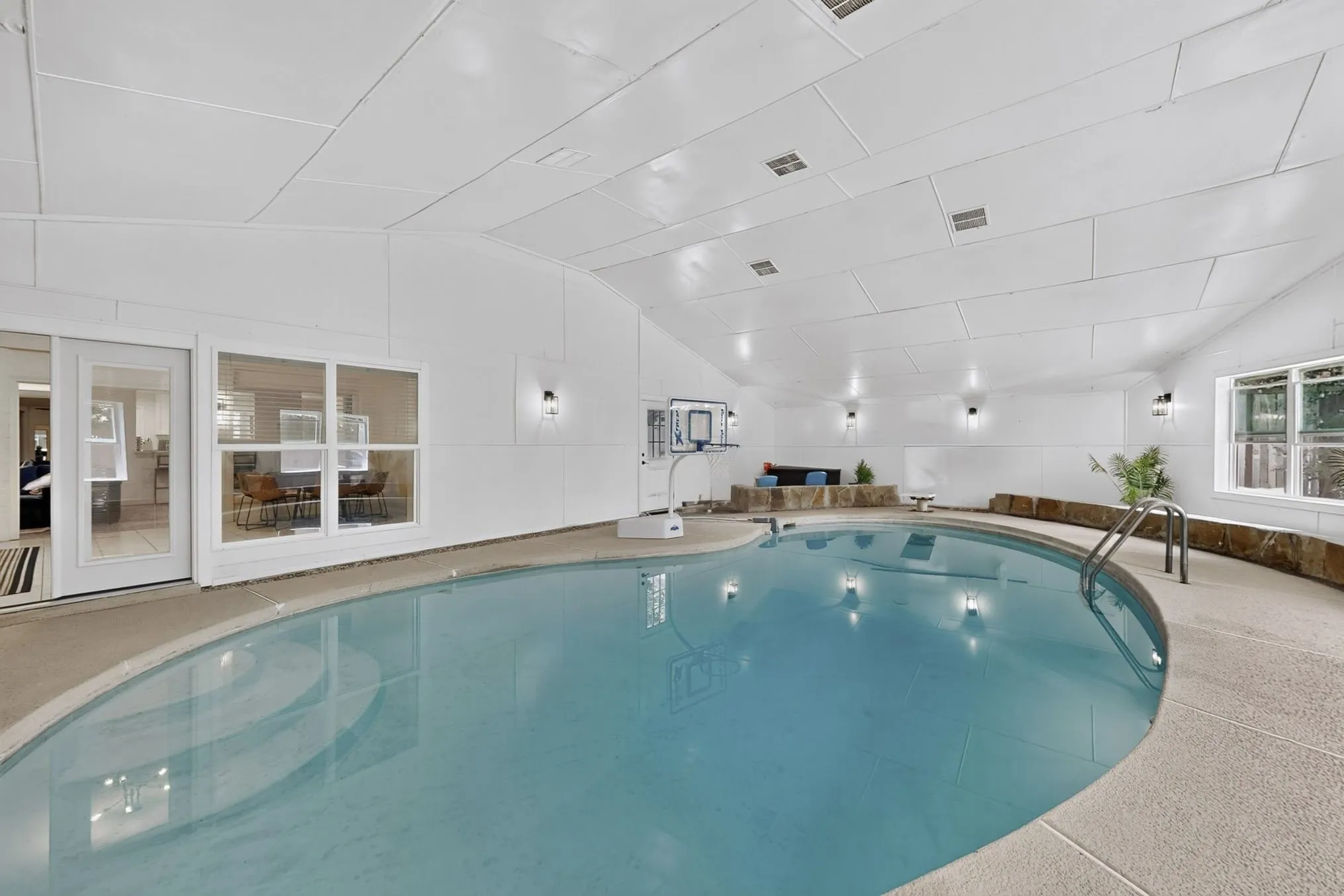 Indoor swimming pool with integrated steps, surrounded by a textured concrete deck