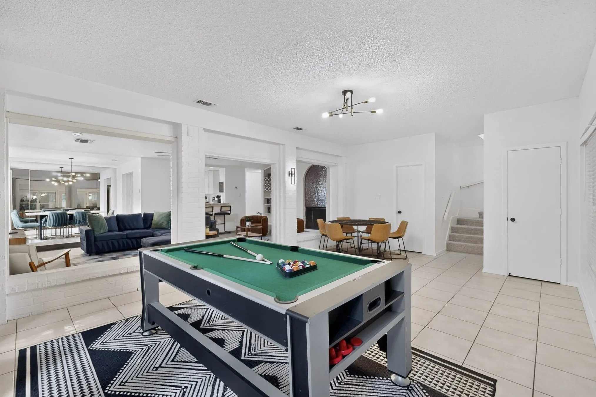 Recessed lighting, tile flooring, modern ceiling light fixture, and a staircase with railing