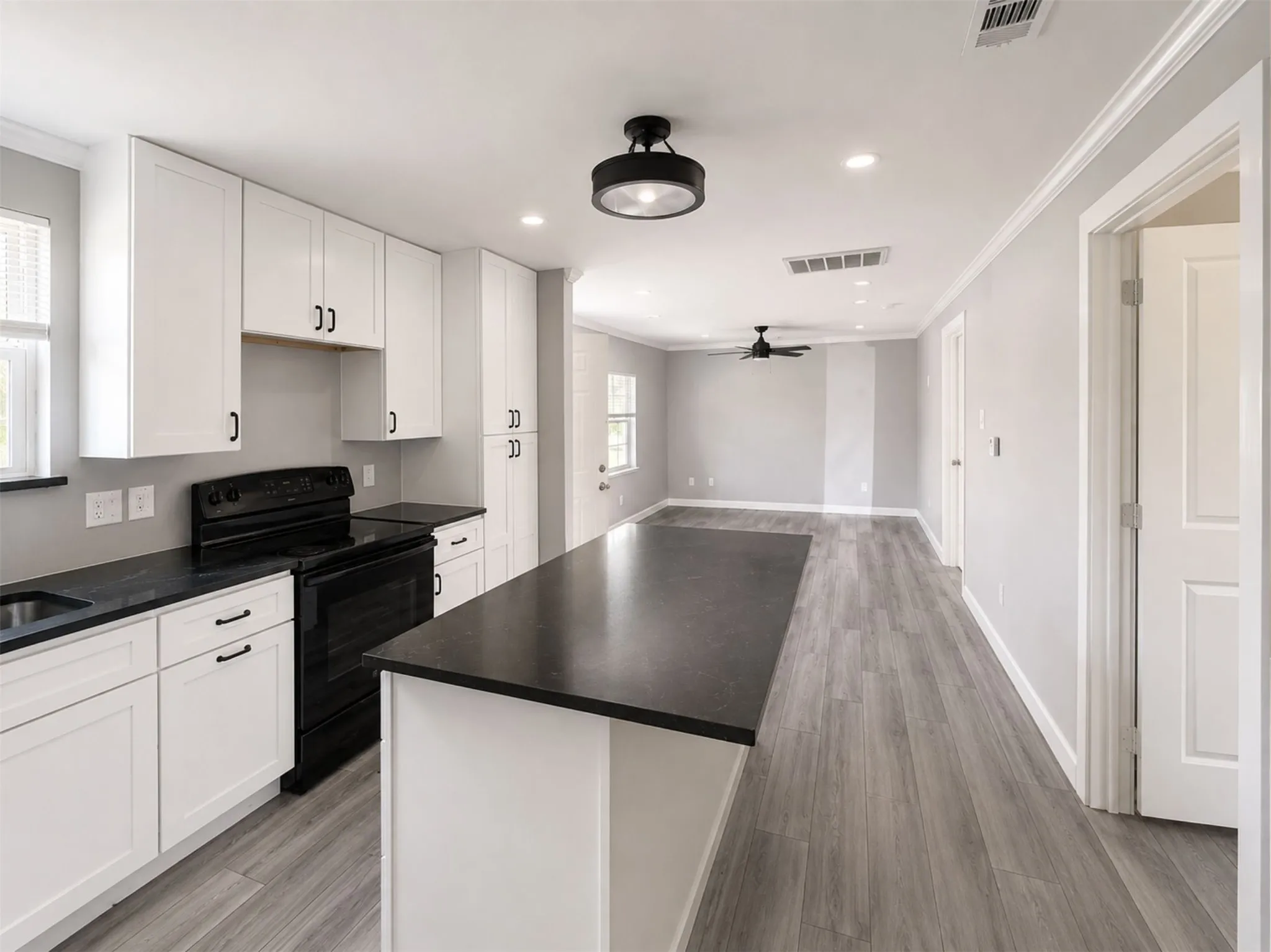 White cabinetry, dark countertops, a kitchen island, wood-finish flooring, and recessed lighting