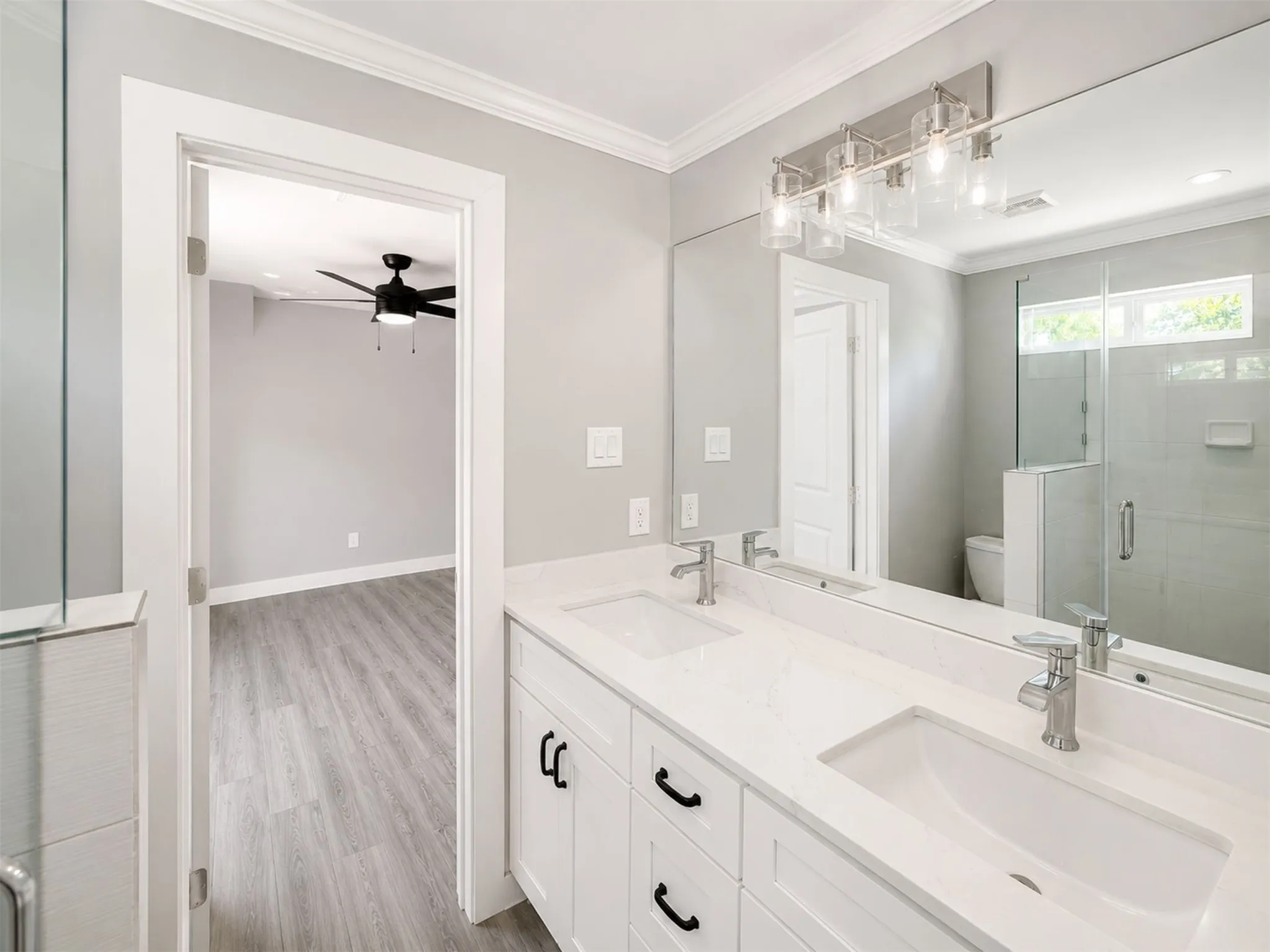 Dual vanity with integrated sinks and brushed nickel faucets, set against a large wall-mounted mirror