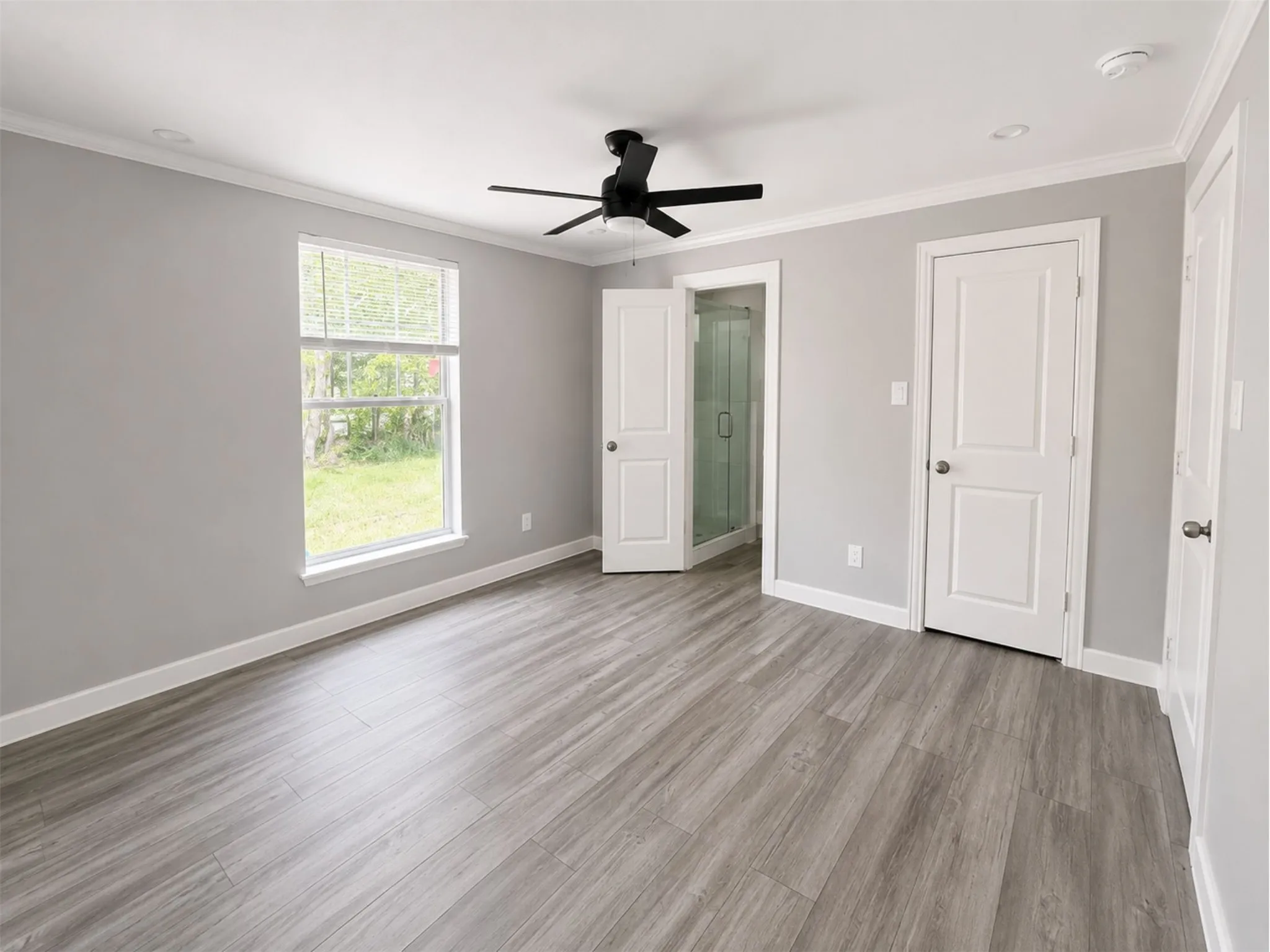 Spacious room featuring wood-finish flooring, a modern black ceiling fan, recessed lighting, and white trim