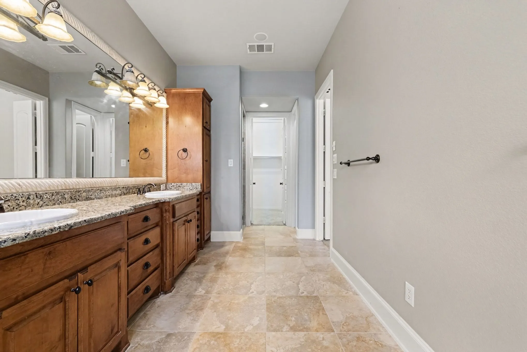 Dual vanity with wood cabinetry, granite-finish countertop, and integrated sinks