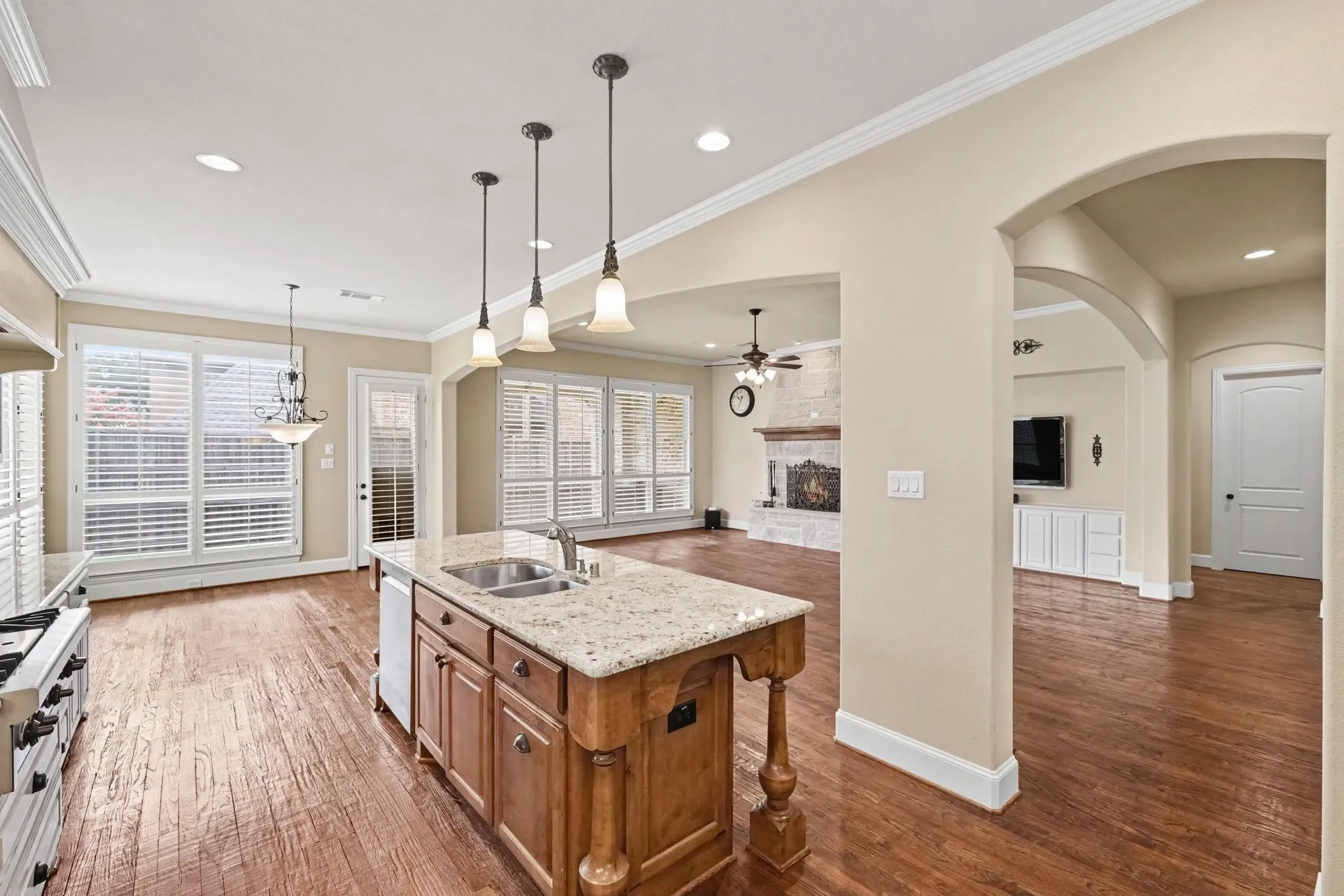 Kitchen island featuring granite-style countertops, dual basin sink, and pendant lighting
