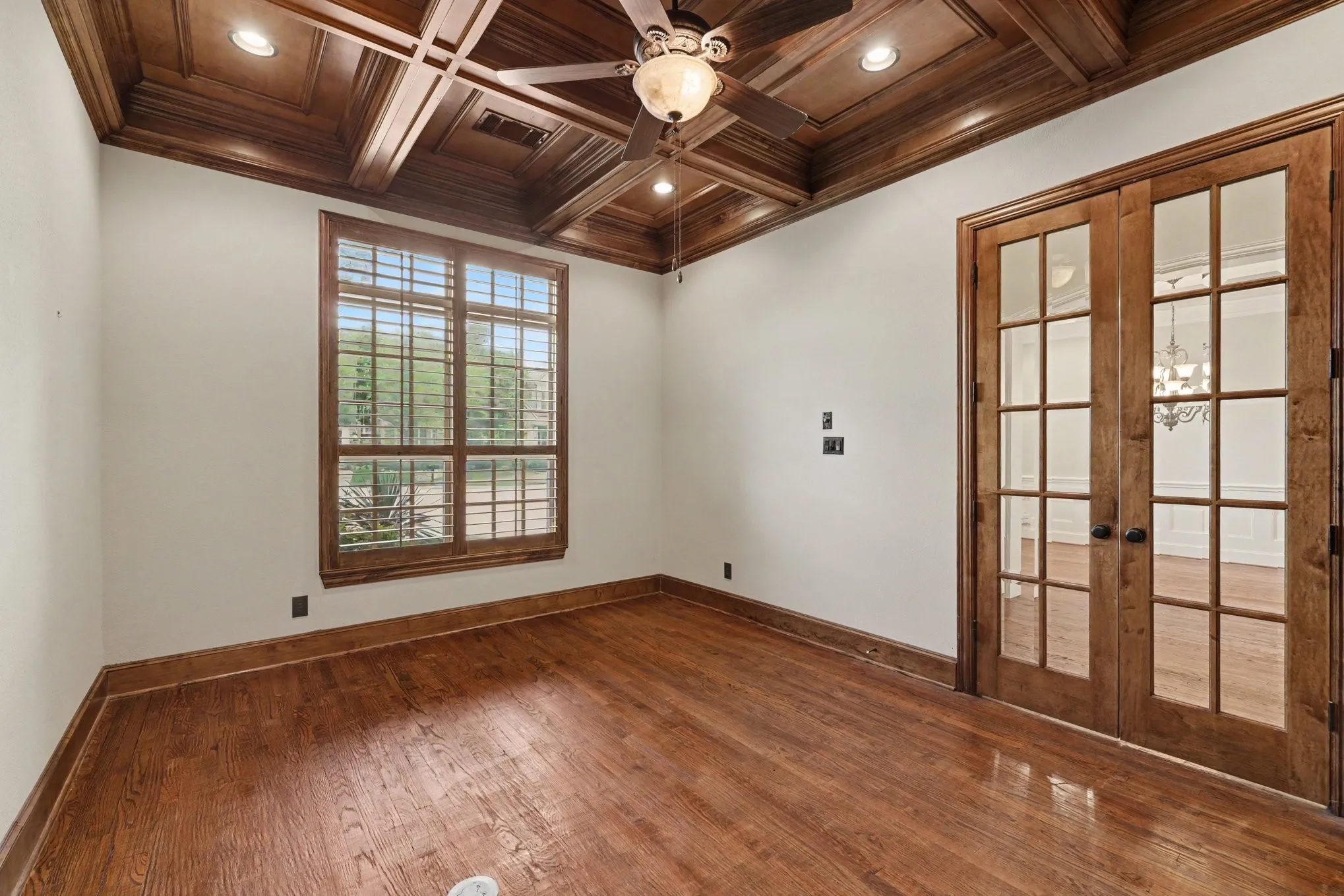 Hardwood flooring and a coffered wood-finish ceiling with recessed lighting