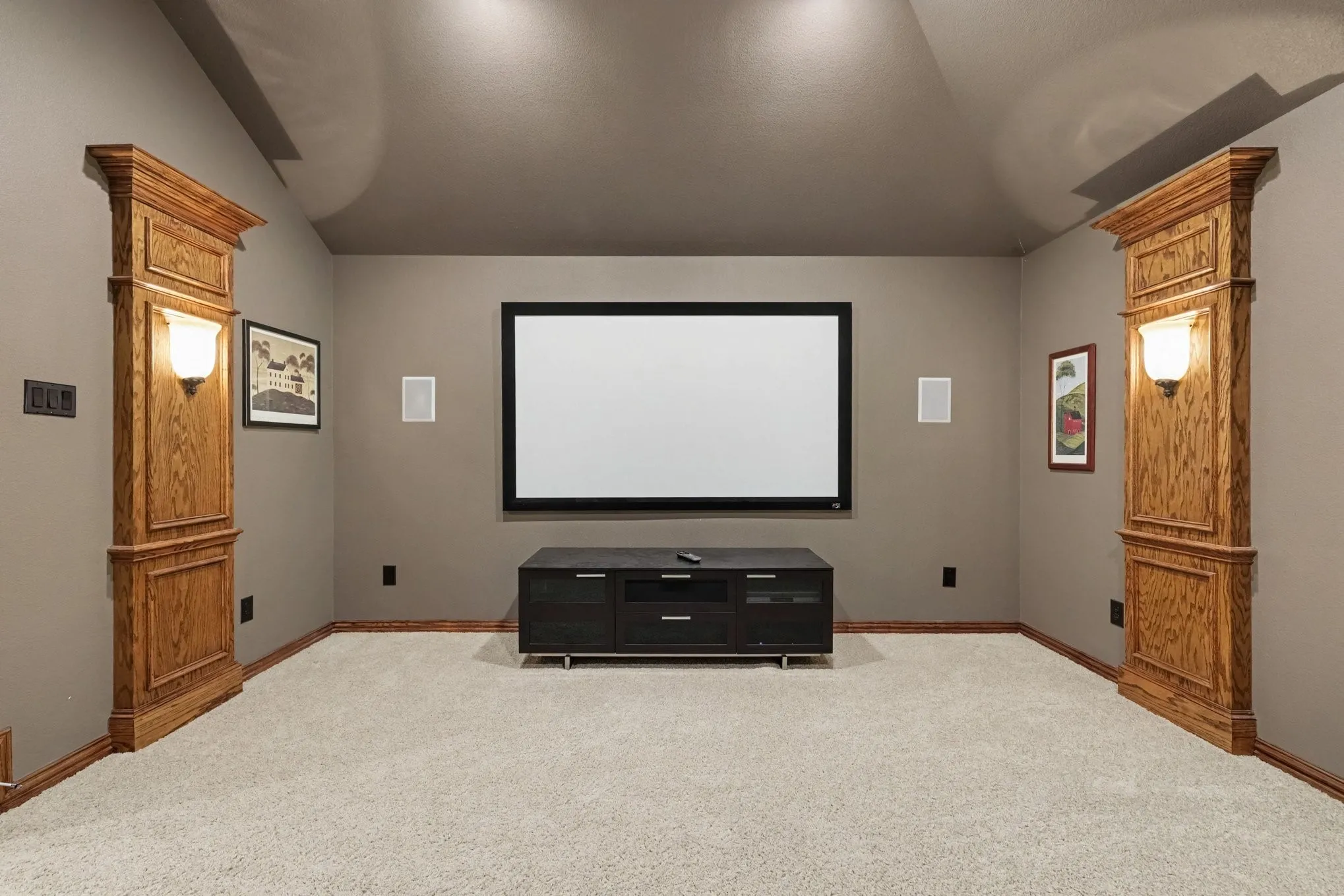 Dedicated media room featuring a large projection screen, recessed ceiling lighting, and built-in wall sconces with wood-finish paneling