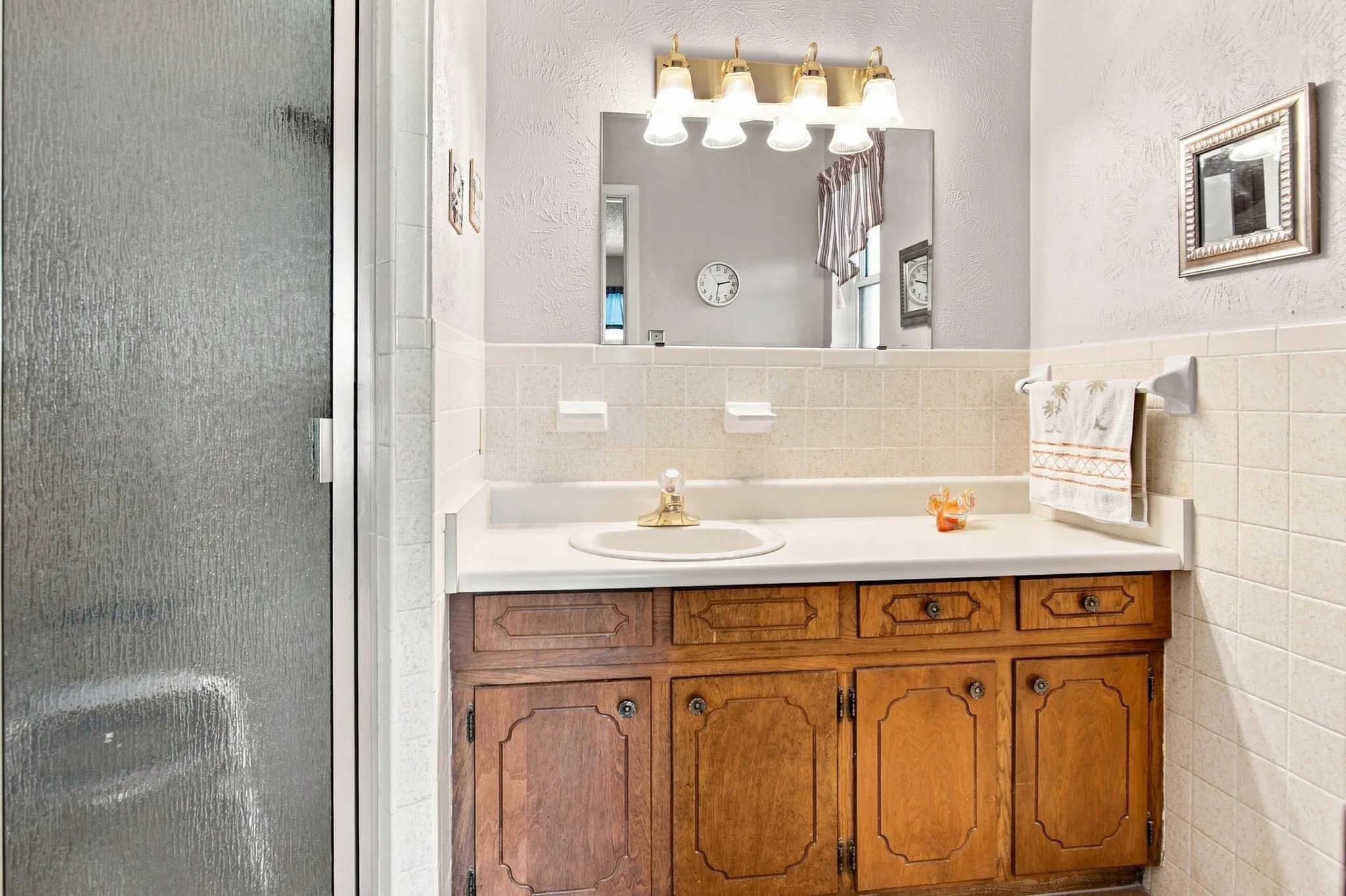 White countertop vanity with wood-finish cabinetry and brass-tone hardware