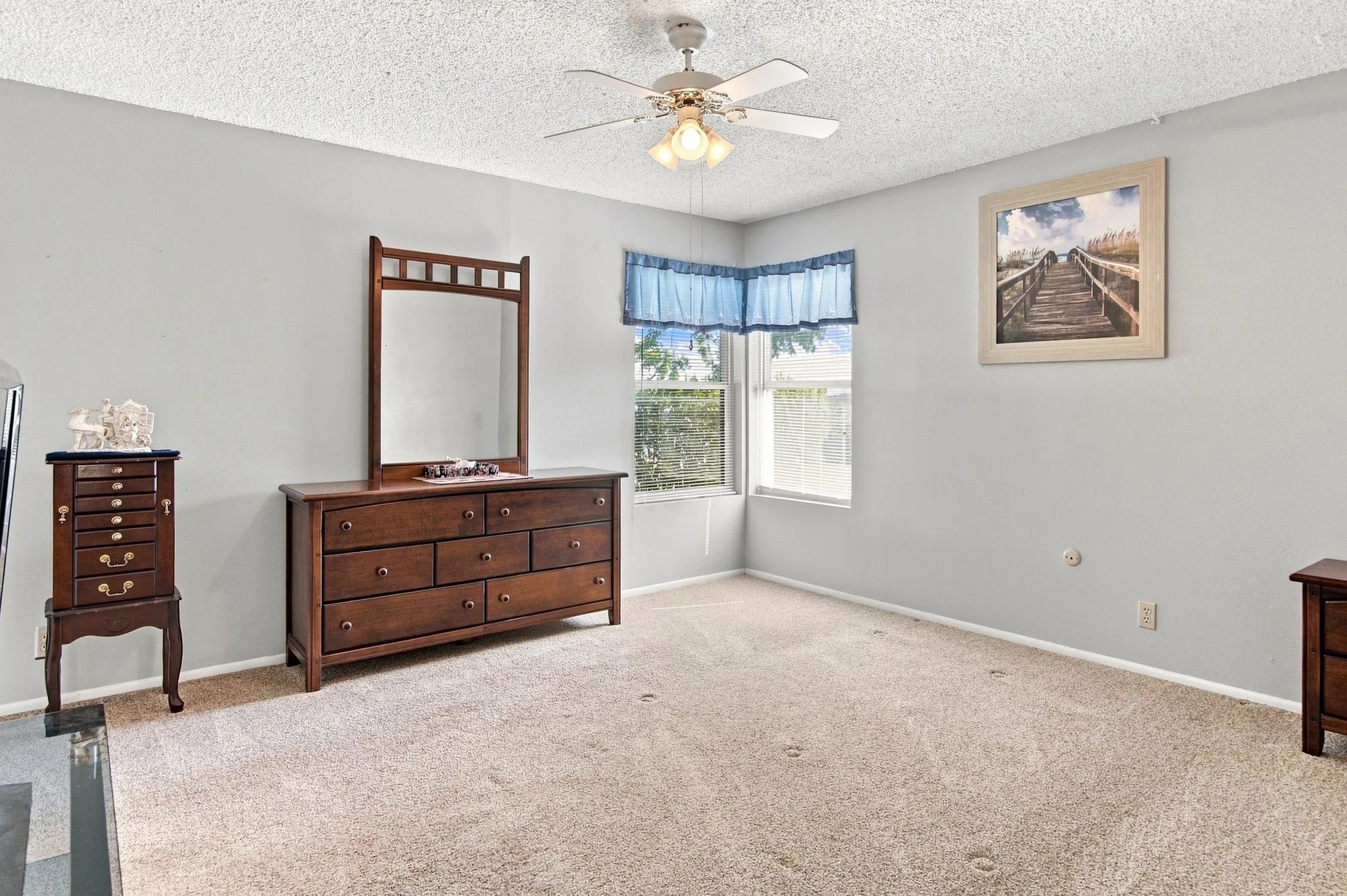 Carpeted flooring, corner window, ceiling fan with integrated lighting, and light-toned wall paint