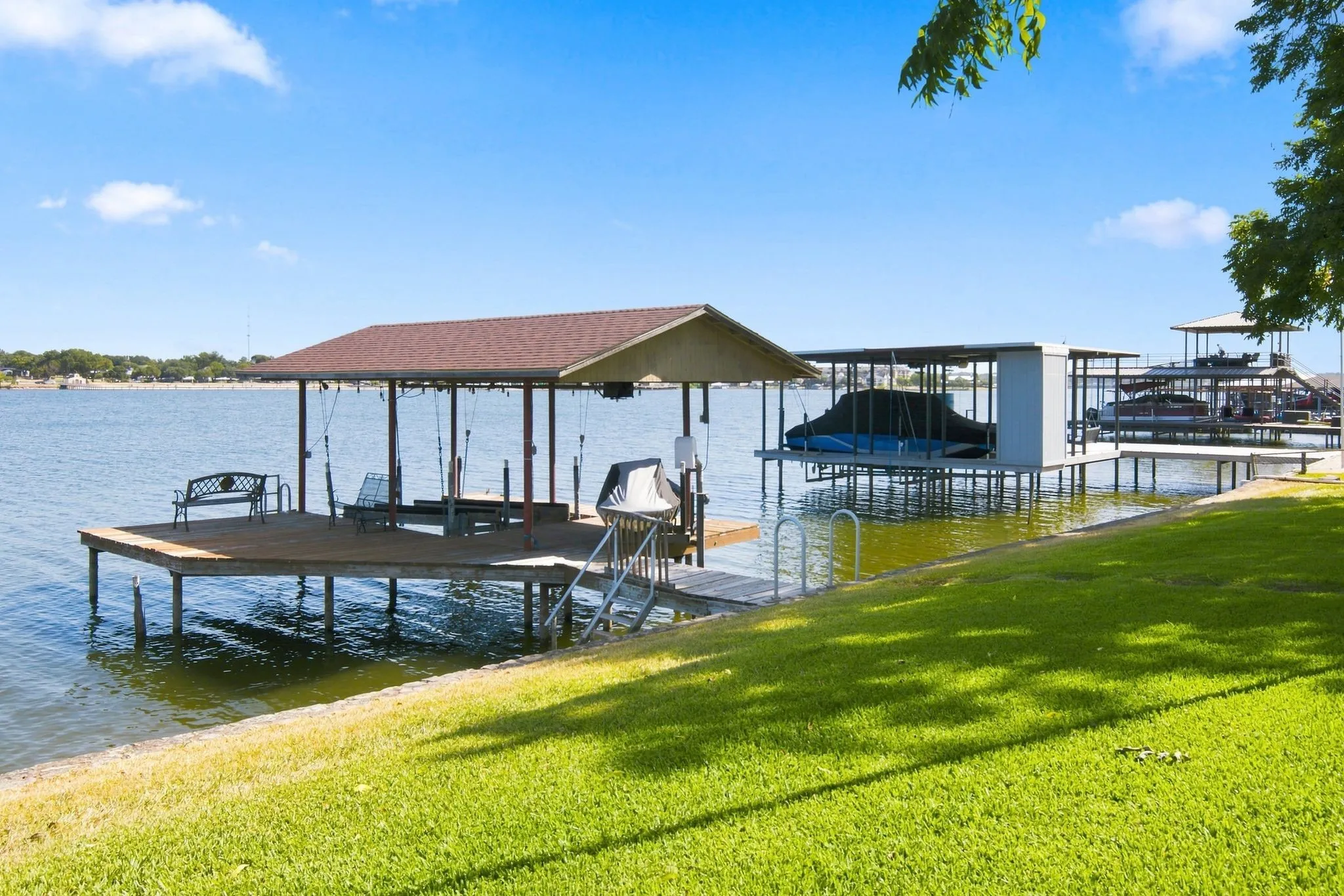 Waterfront property featuring a covered dock, boat lift, and a private staircase to the water
