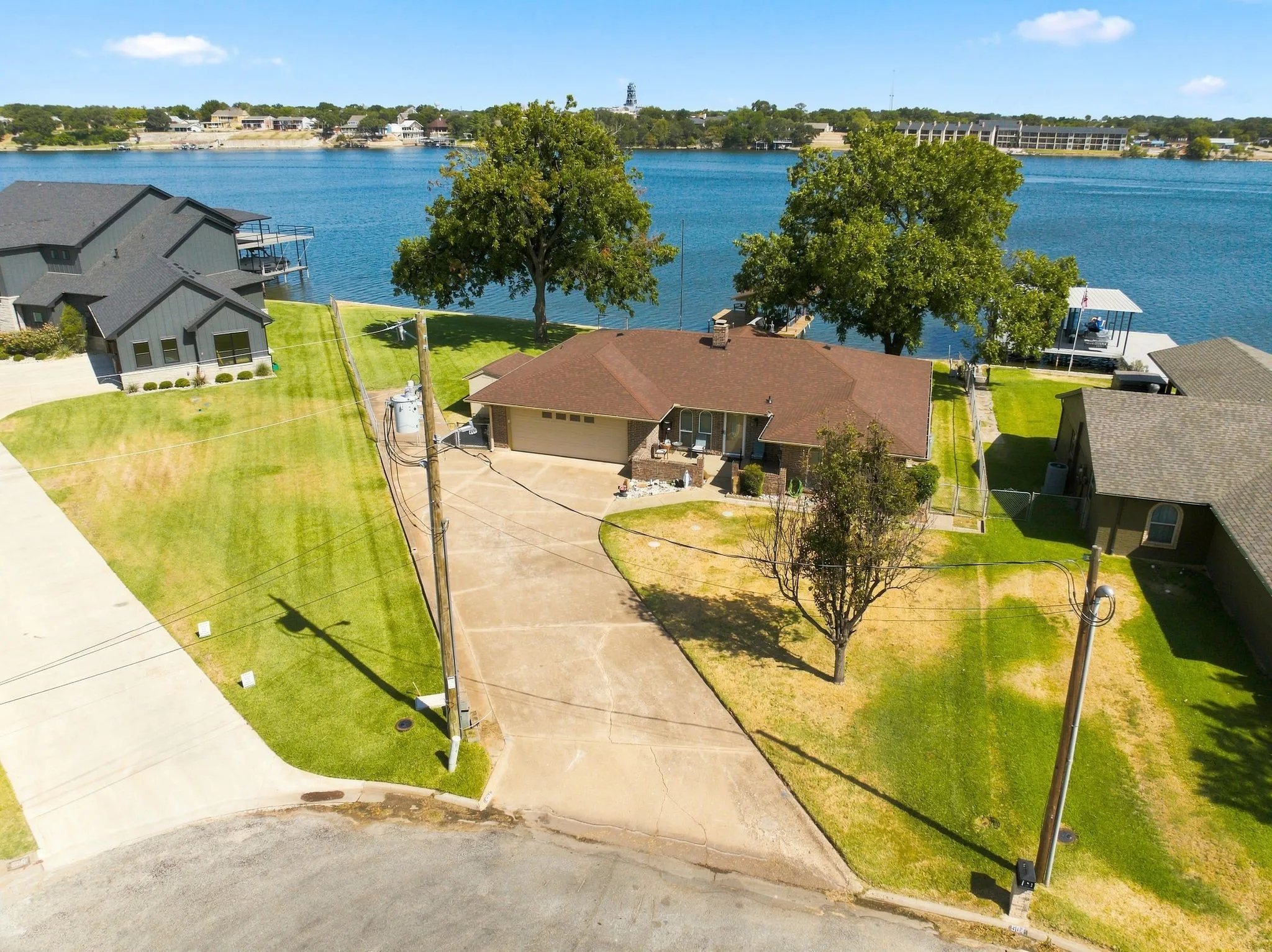 Waterfront property with boat dock, manicured lawn, and mature trees