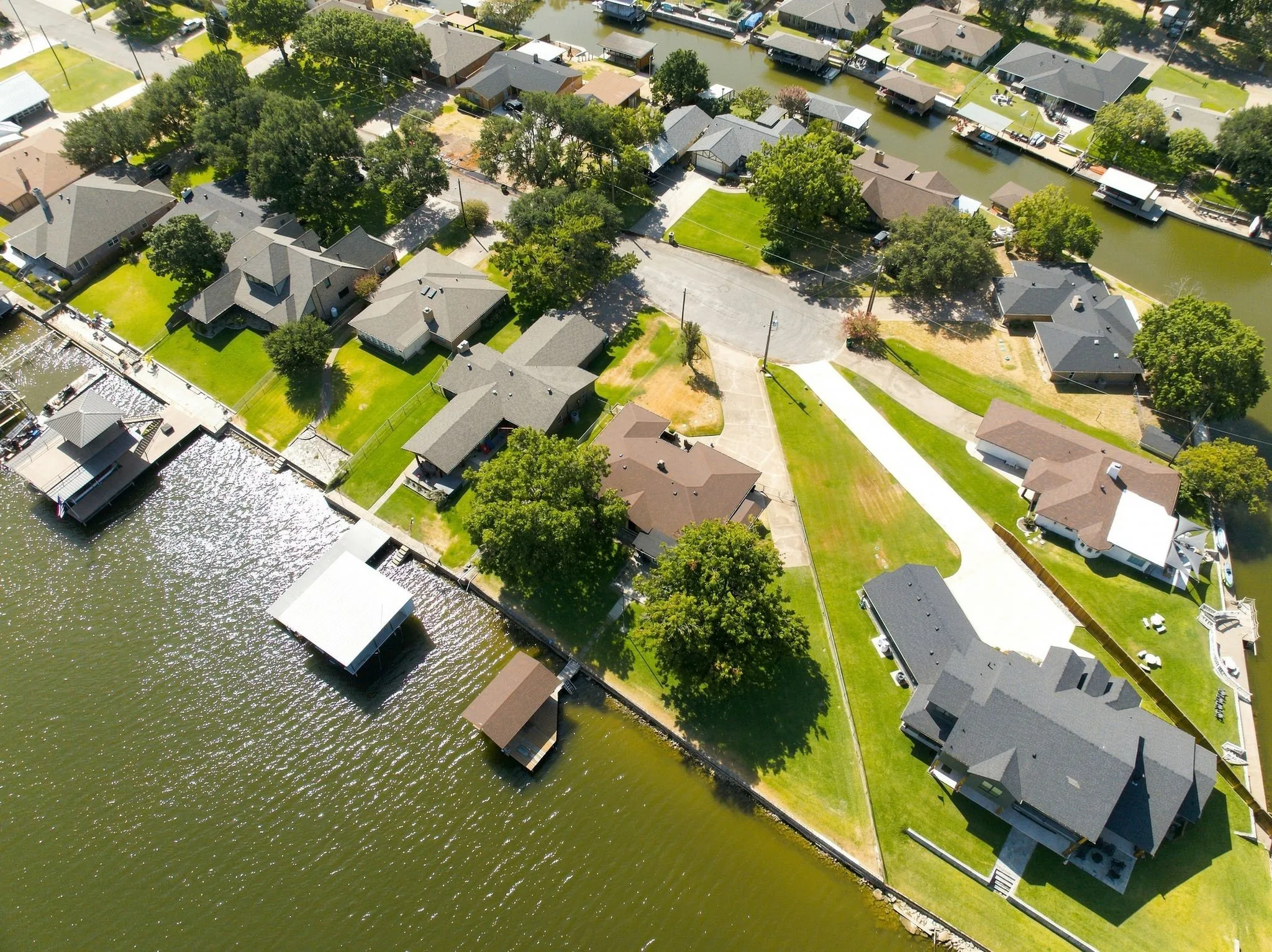 Waterfront property featuring multiple boat slips, a private boat house, and lush green lawns