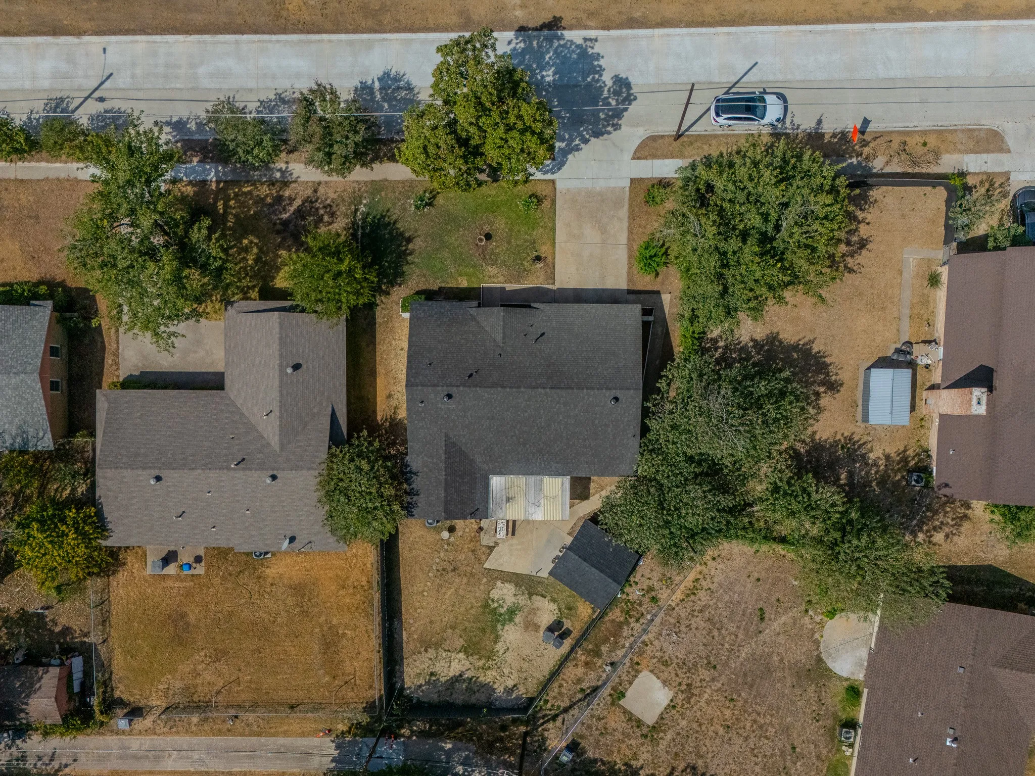Asphalt shingle roof, paved driveway, mature trees, concrete patio, detached storage shed