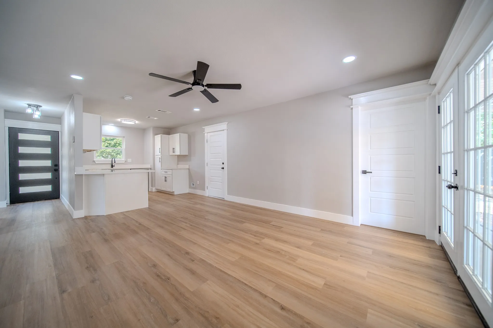 Open-concept living space with wood-finish flooring, recessed lighting, and a ceiling fan