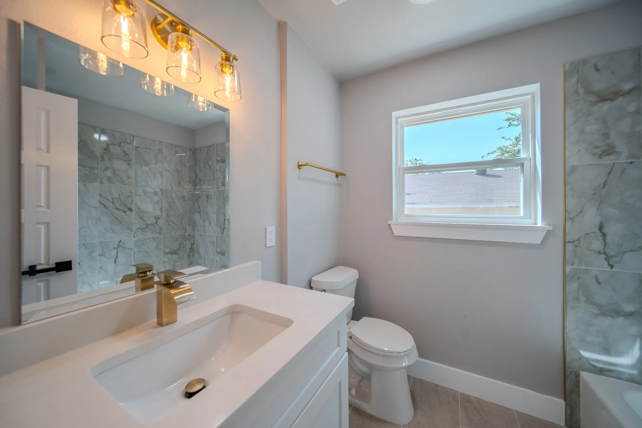 Vanity with integrated sink, gold-finish faucet, and coordinating overhead lighting