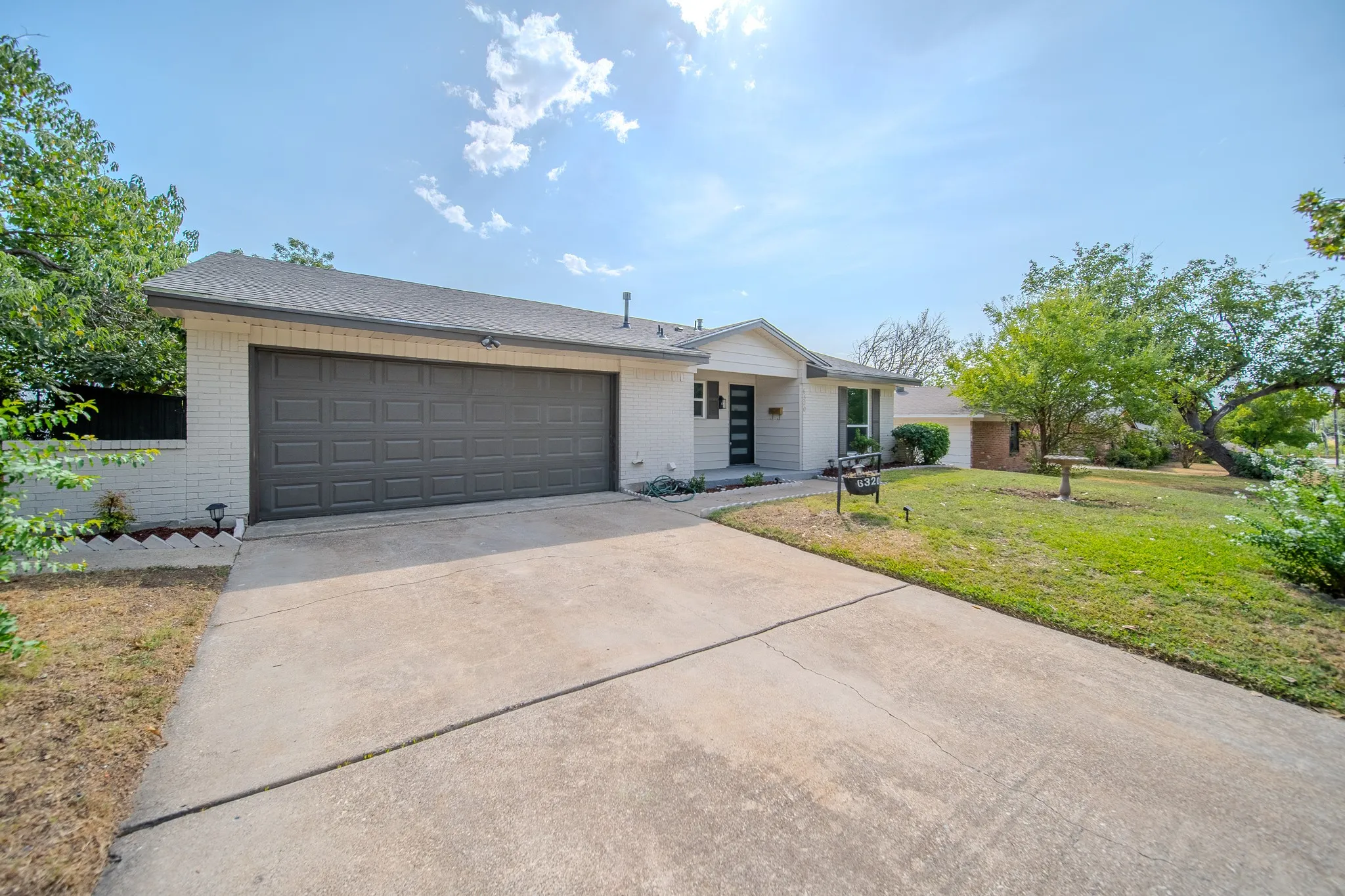 Single-story residence featuring a two-car garage, concrete driveway, and a white brick exterior