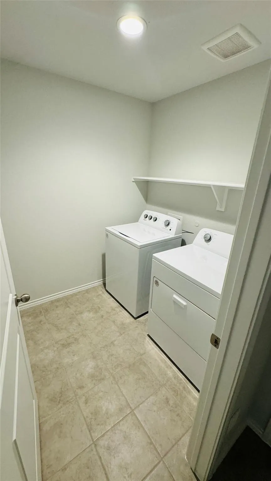 Recessed ceiling light, wall-mounted shelving, and tile flooring