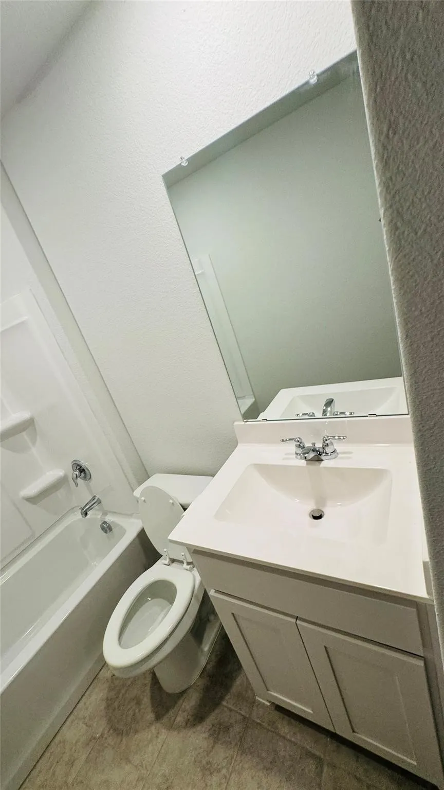 White vanity with integrated sink, chrome faucet, wall-mounted mirror, and white bathtub with chrome fixtures