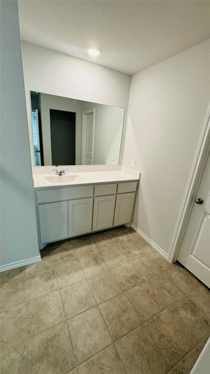 Vanity with built-in cabinetry, integrated sink, and expansive mirror