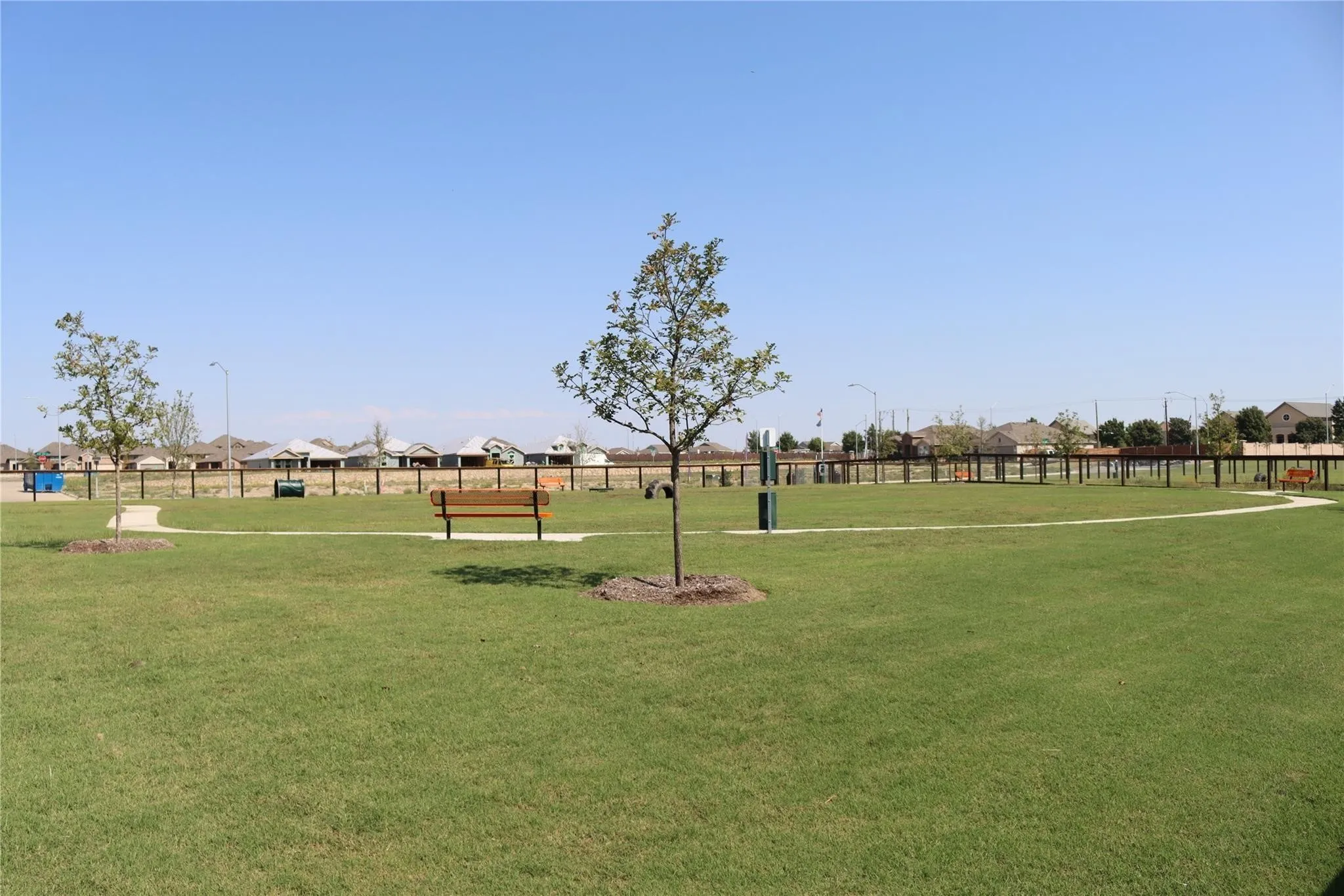 Expansive green space featuring established trees, walking paths, and perimeter fencing