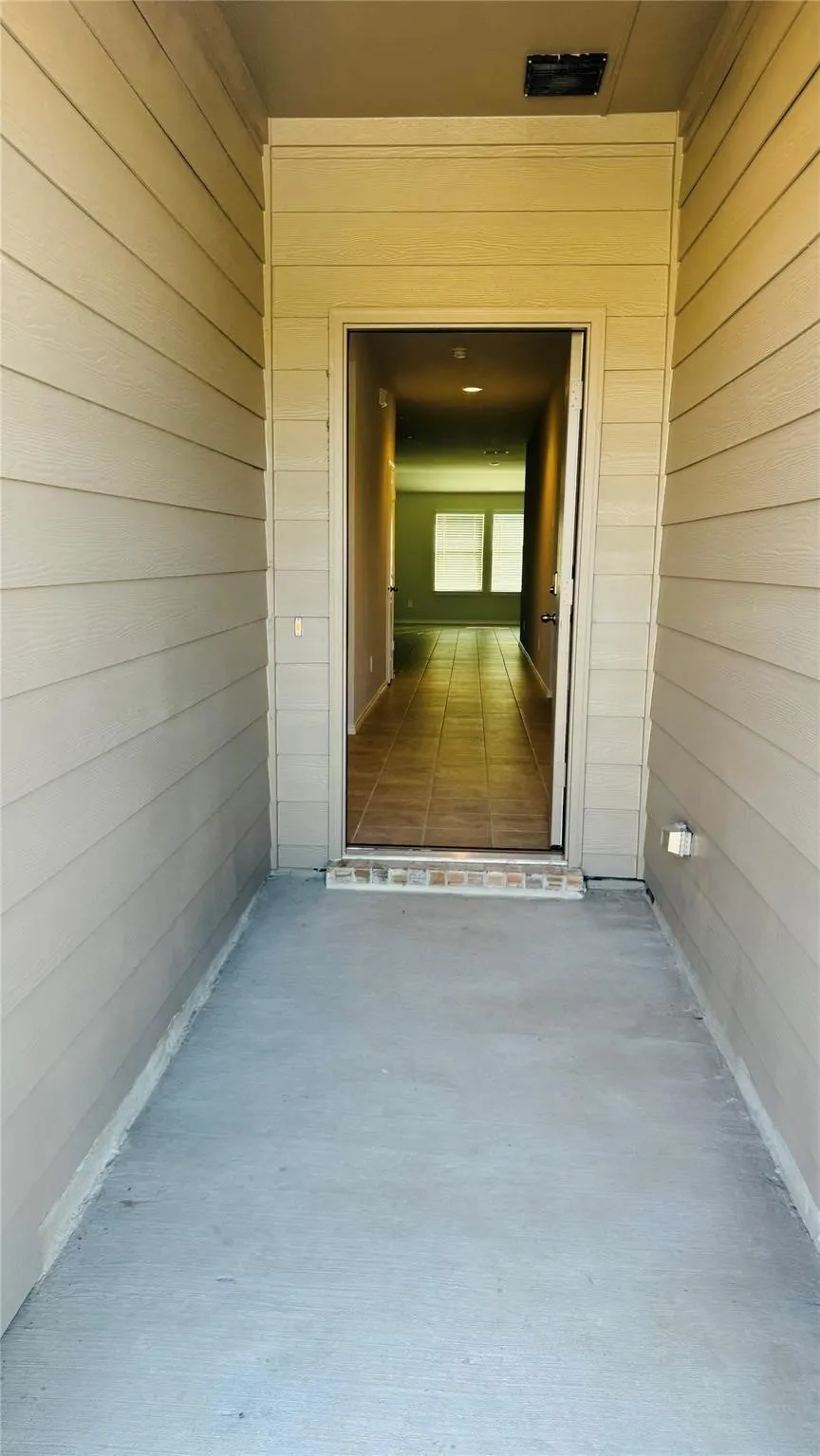 Entryway with light-toned siding and a concrete porch