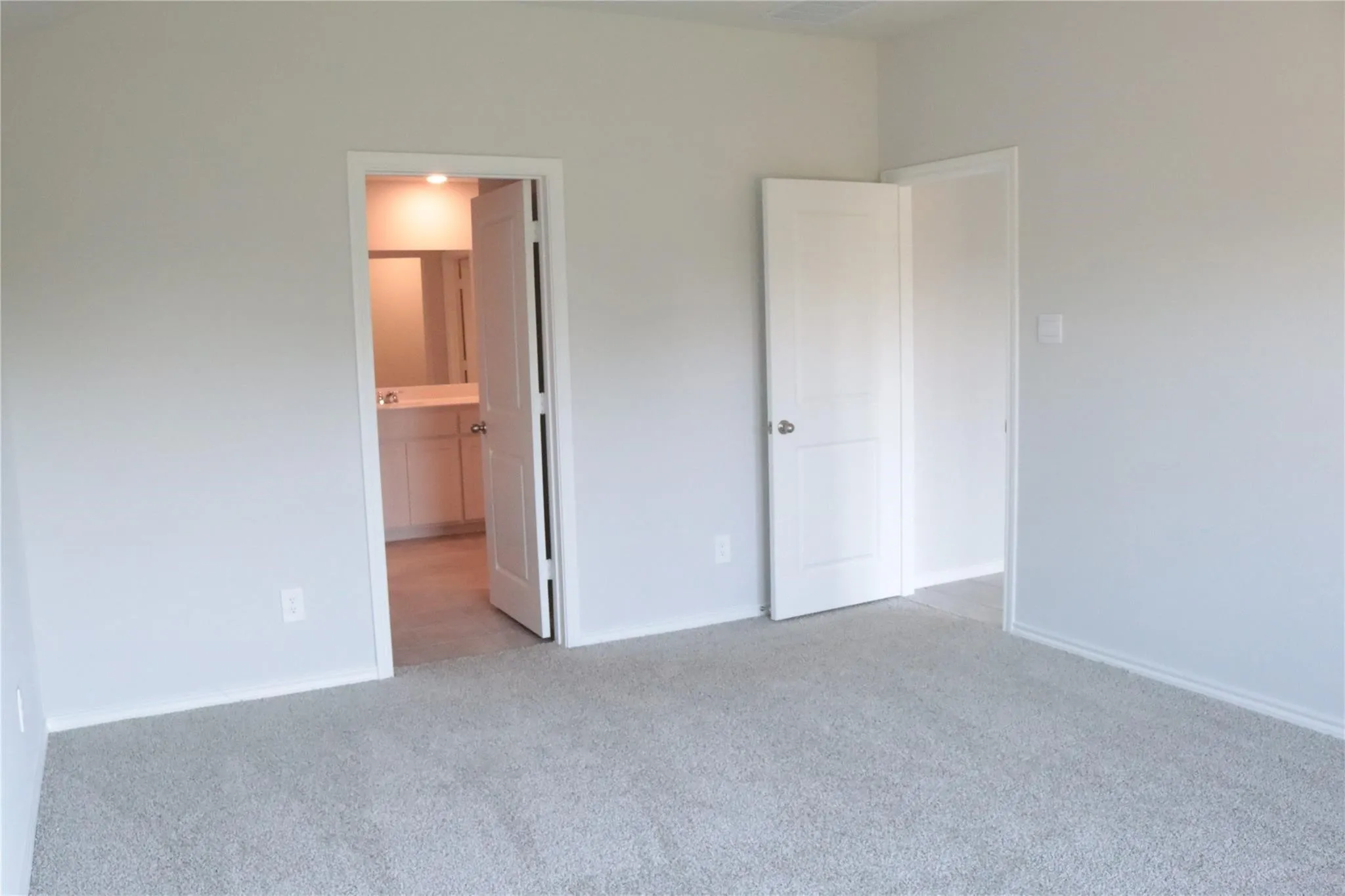 Neutral tone wall paint, light gray carpeting, white interior doors, and recessed lighting in the adjacent space