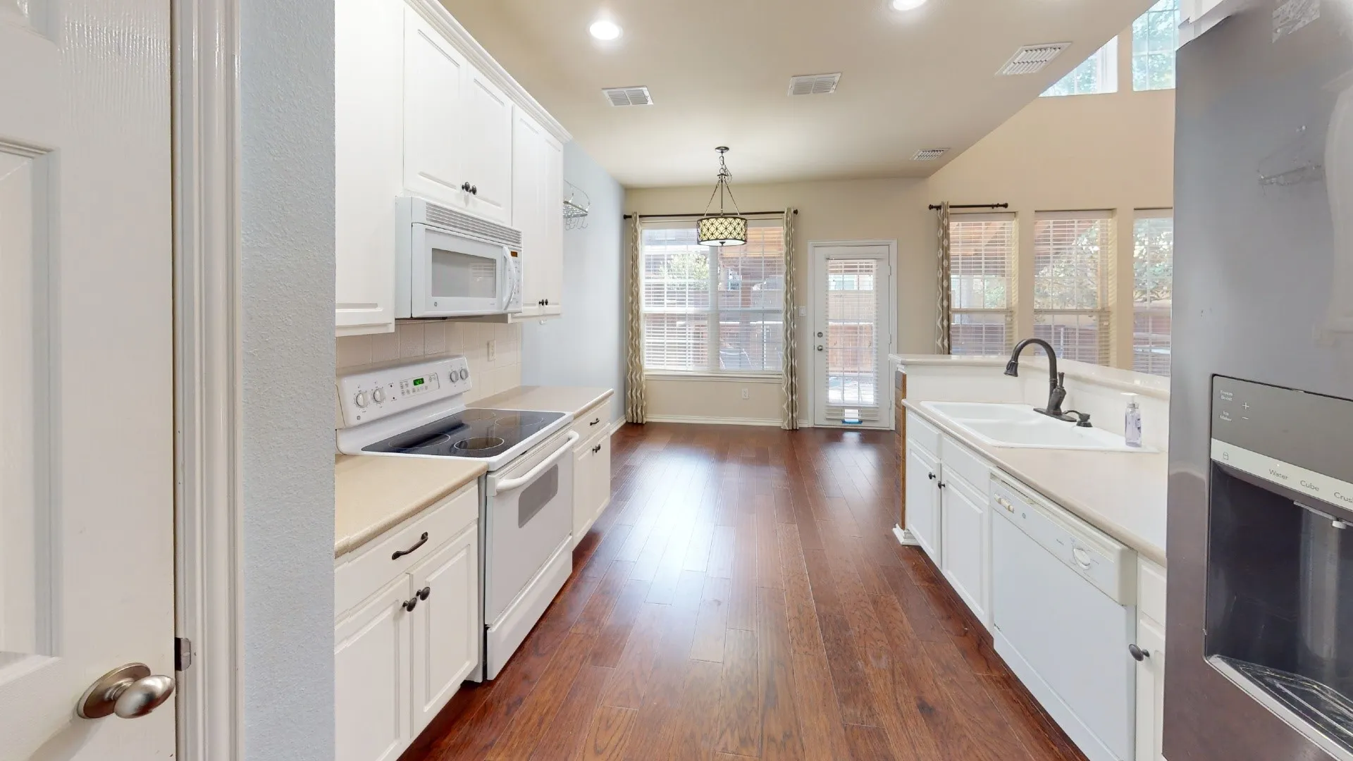 Kitchen featuring white cabinetry, light-colored countertops, stainless steel refrigerator, and wood-finish flooring