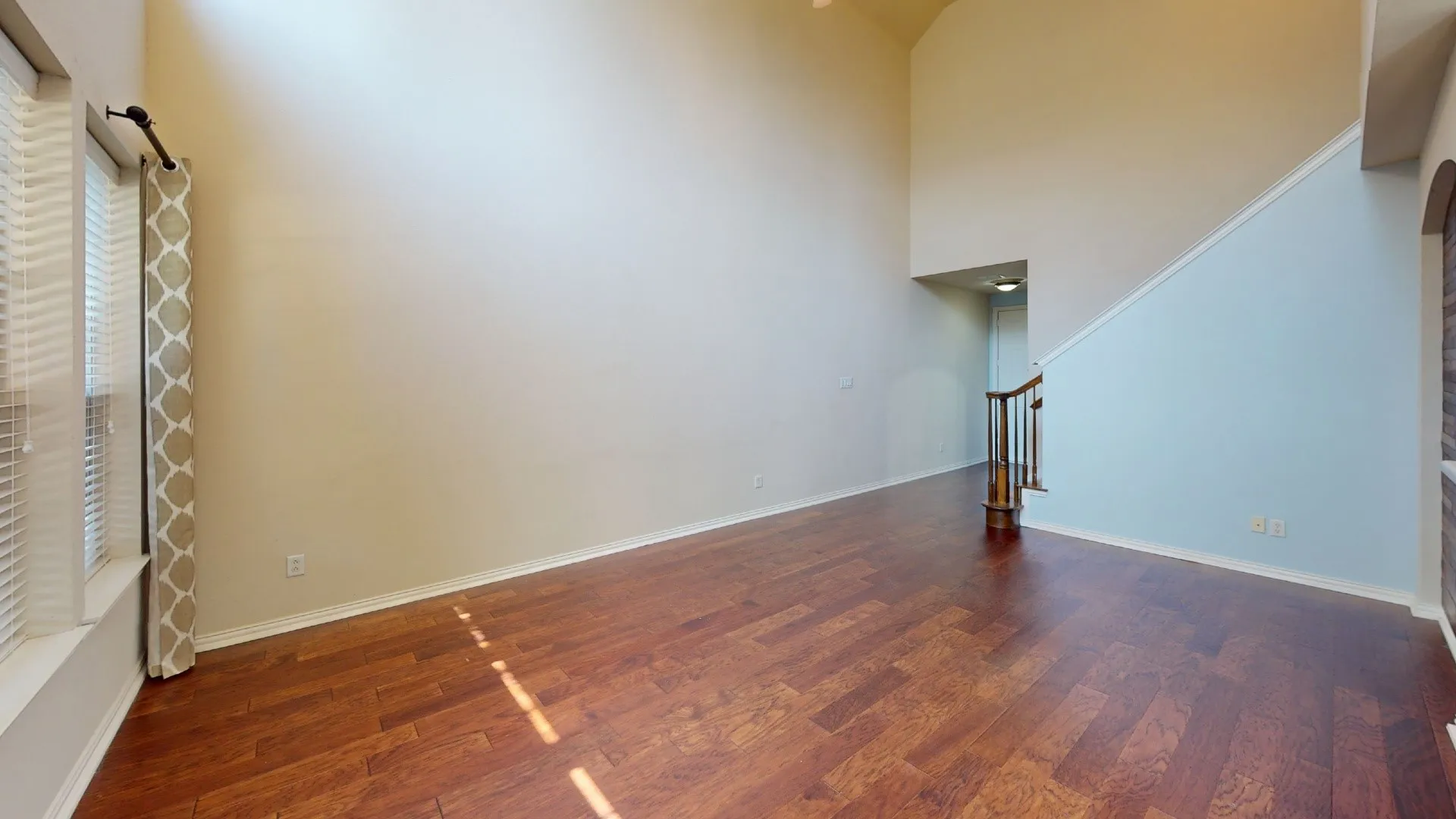 High ceilings, wood-finish flooring, staircase with wood railing, and window with blinds