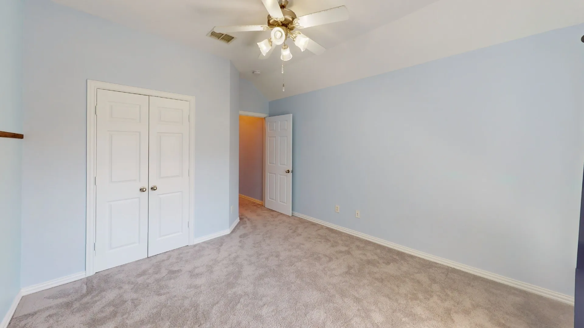 Vaulted ceiling with a ceiling fan, light-toned carpeting, and a double-door closet with polished hardware