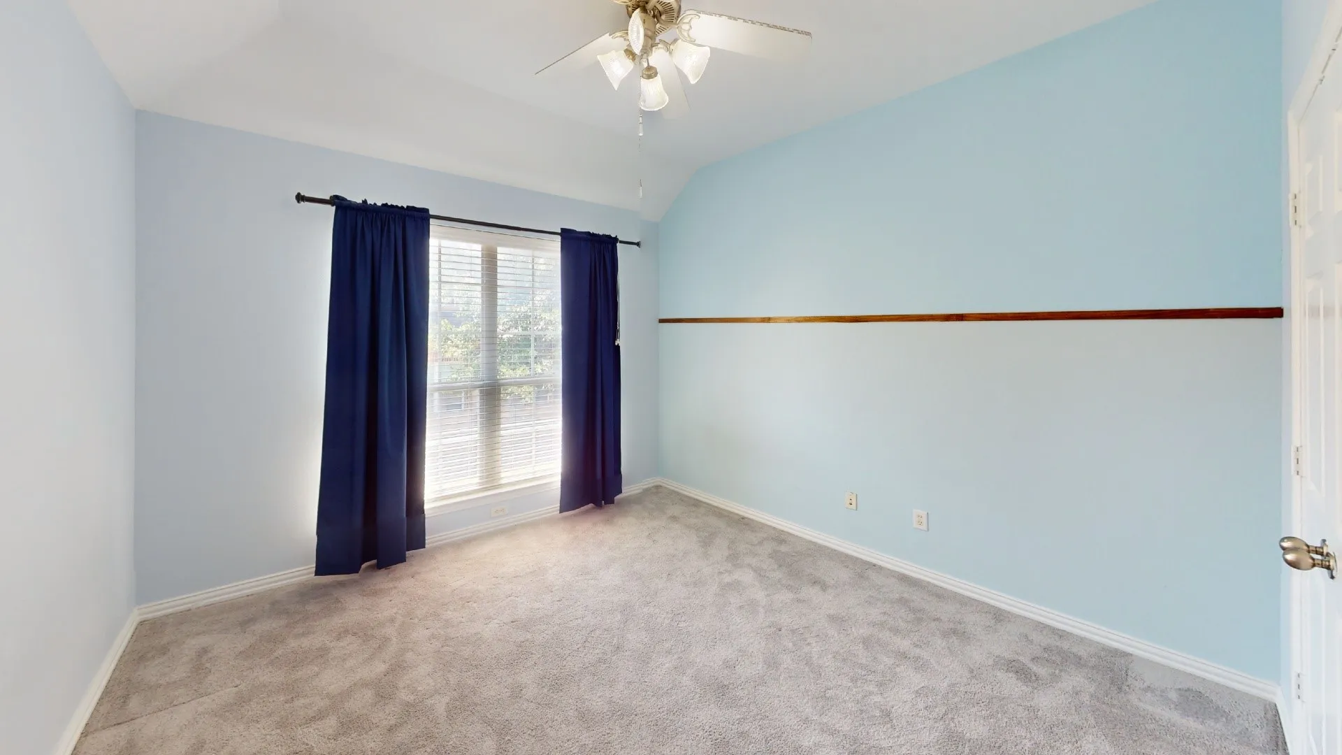 Carpeted flooring, vaulted ceiling, ceiling fan, window with blinds, and decorative wall trim