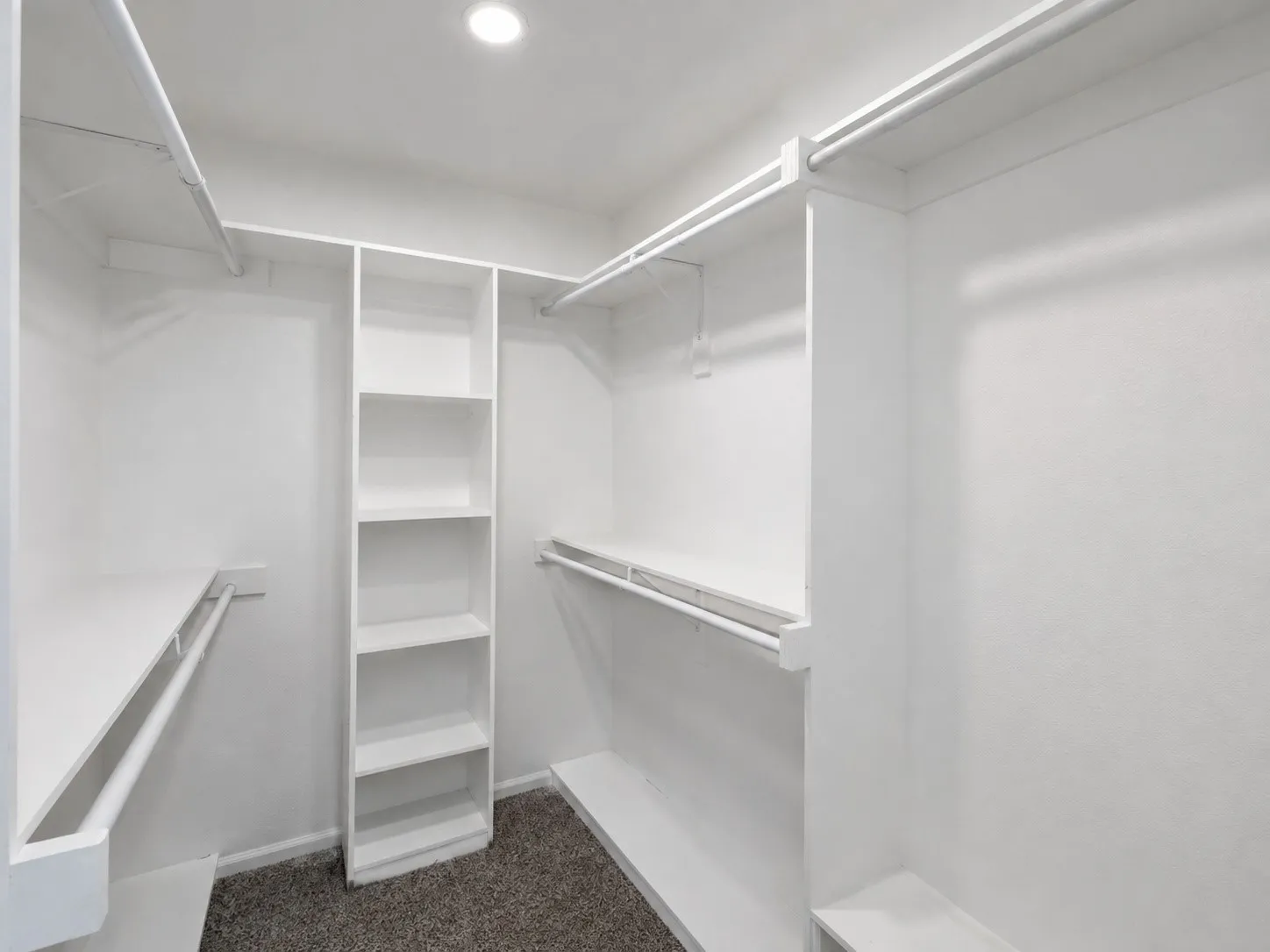 Walk-in closet featuring built-in shelving, multiple hanging rods, and recessed lighting