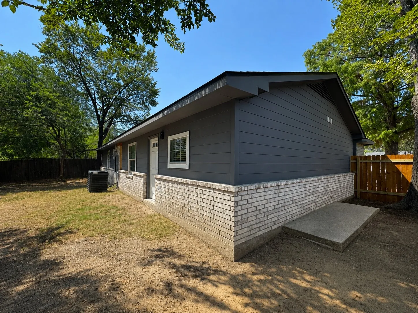 Modern ranch-style home featuring a charcoal fiber cement exterior with contrasting brick veneer foundation