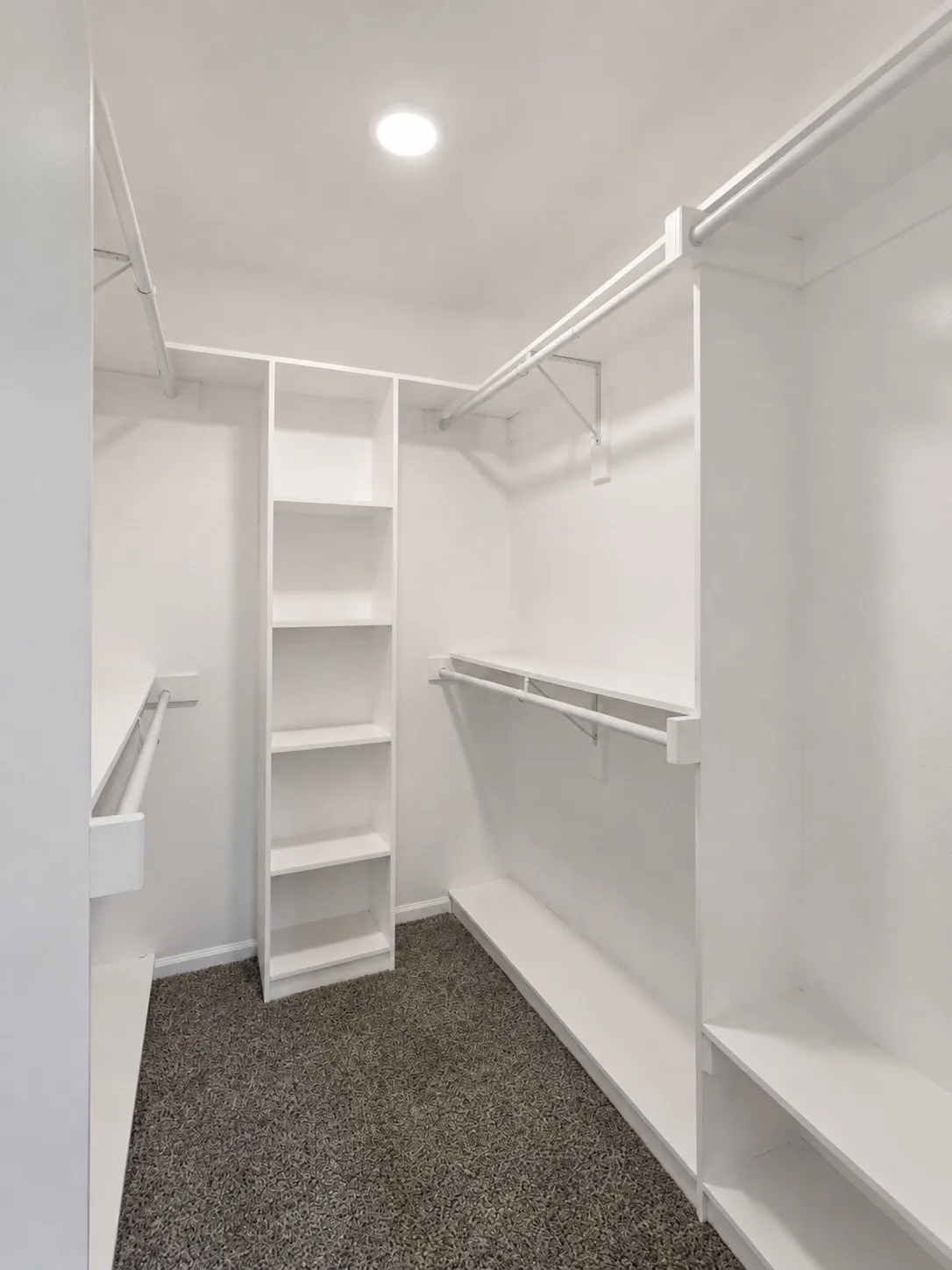 White built-in shelving, multiple hanging rods, and recessed lighting