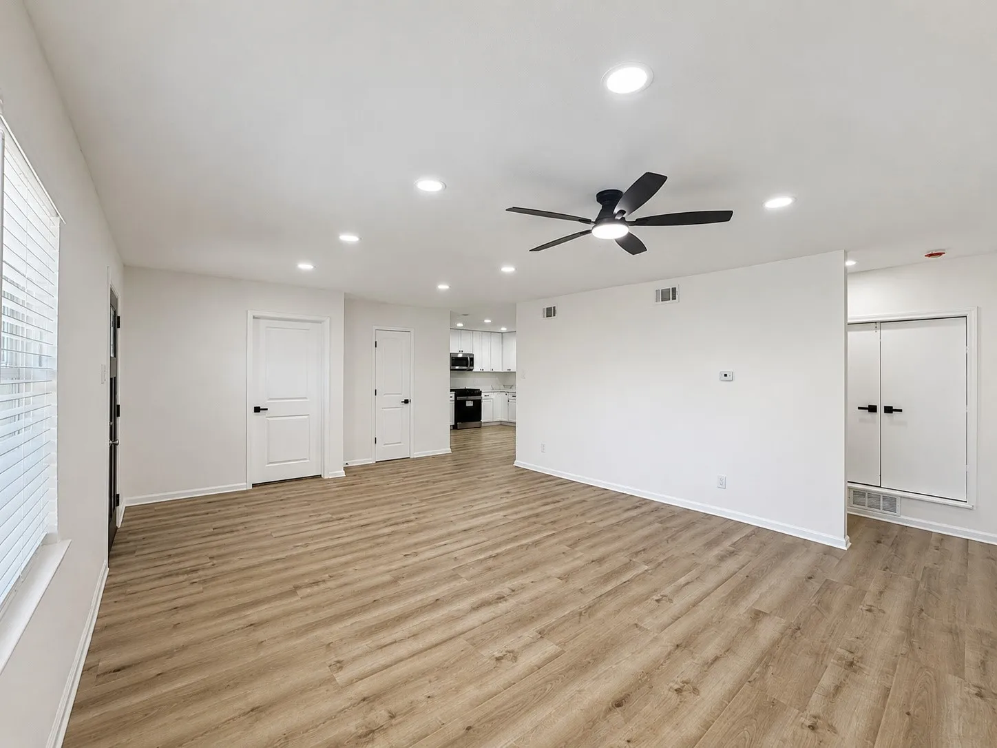 Spacious room with wood-finish flooring, recessed lighting, and a ceiling fan