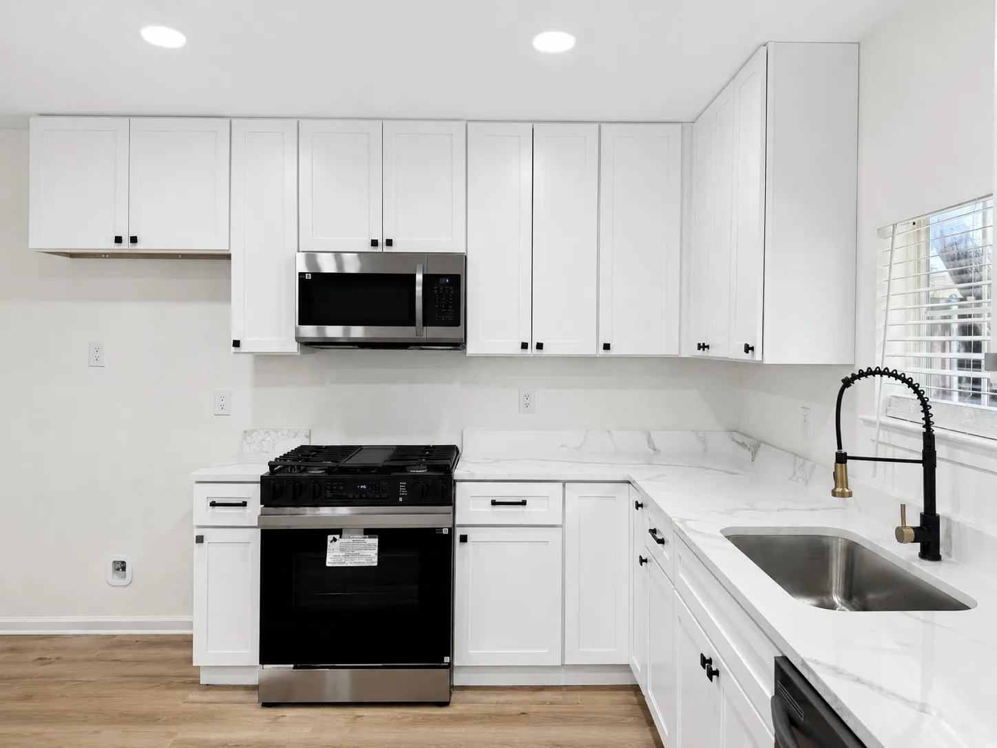 Kitchen featuring white cabinetry, stainless steel appliances, stone countertops, and wood-finish flooring