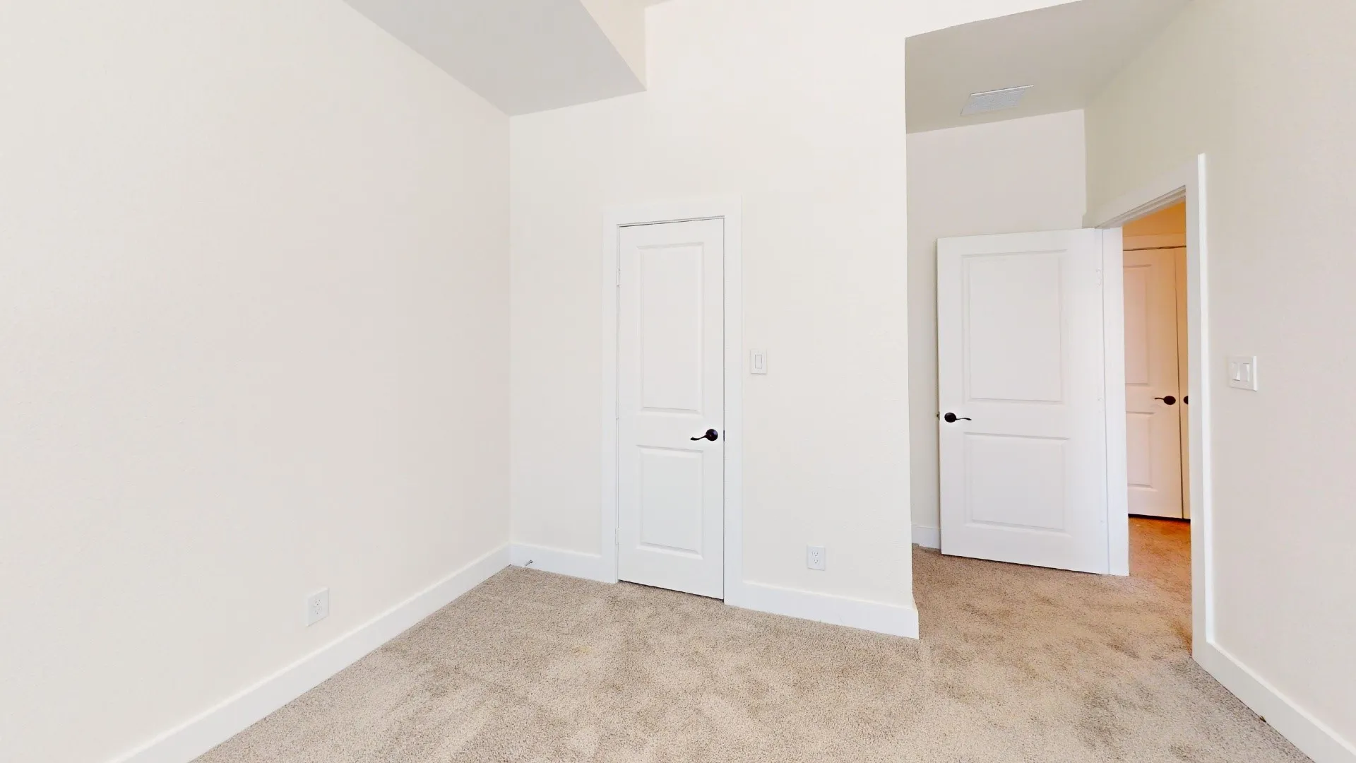 Neutral-toned carpeting and white interior doors with dark hardware
