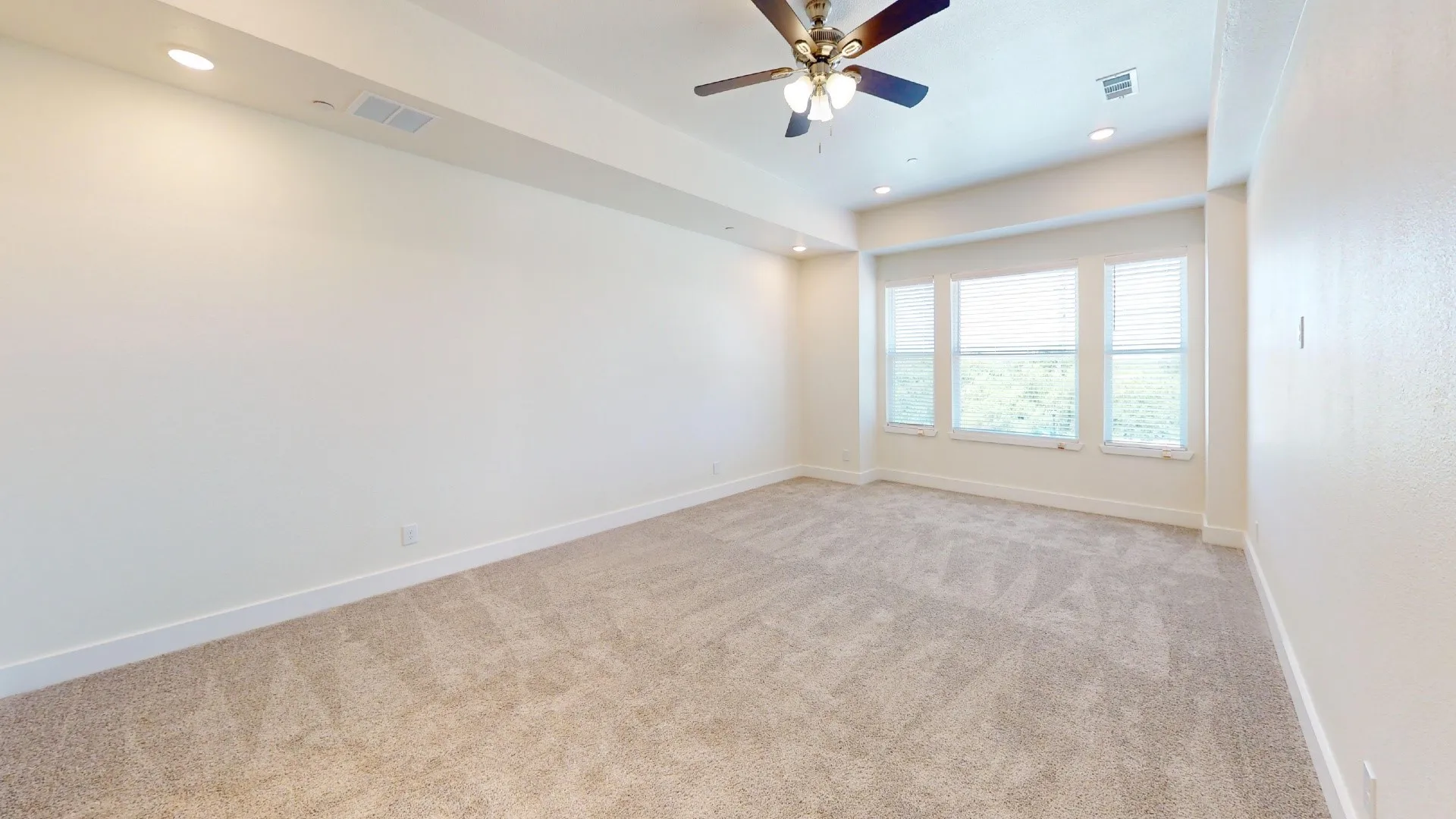 Expansive room featuring recessed lighting, a ceiling fan, plush carpet, and a triple window assembly