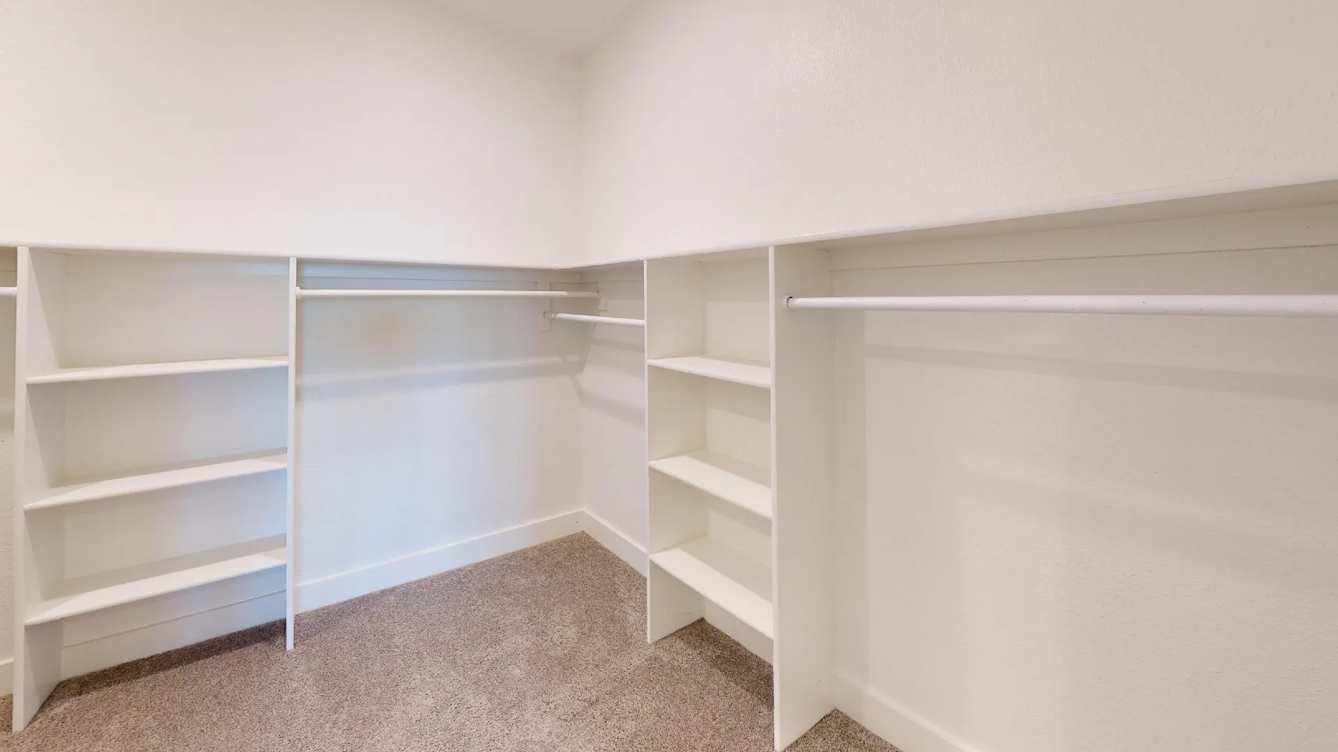 Walk-in closet featuring extensive built-in shelving and hanging rods