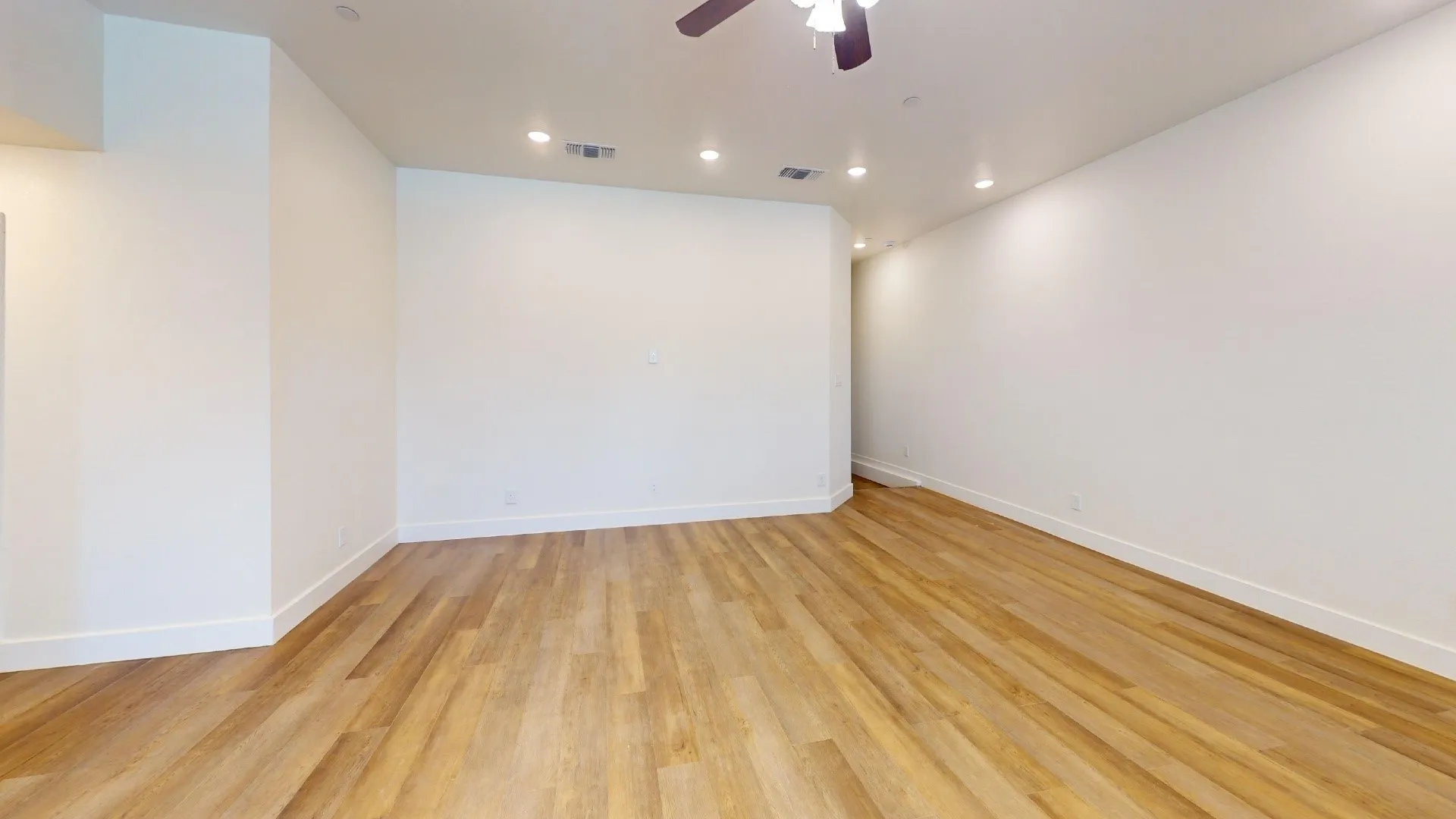 Wood-finish flooring with white baseboards, recessed lighting, and a ceiling fan