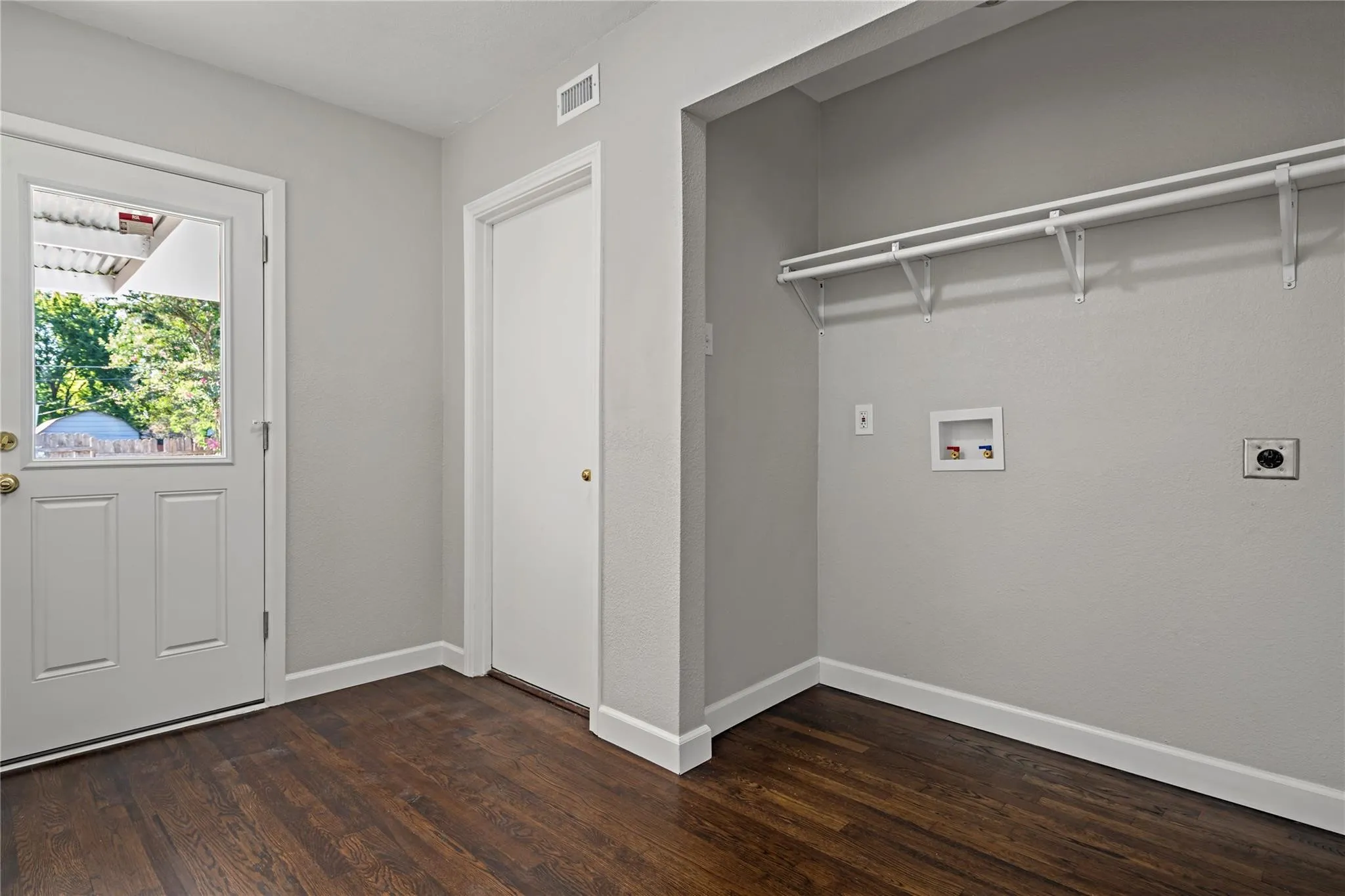 Wood-finish flooring, white trim, and a white paneled door with window