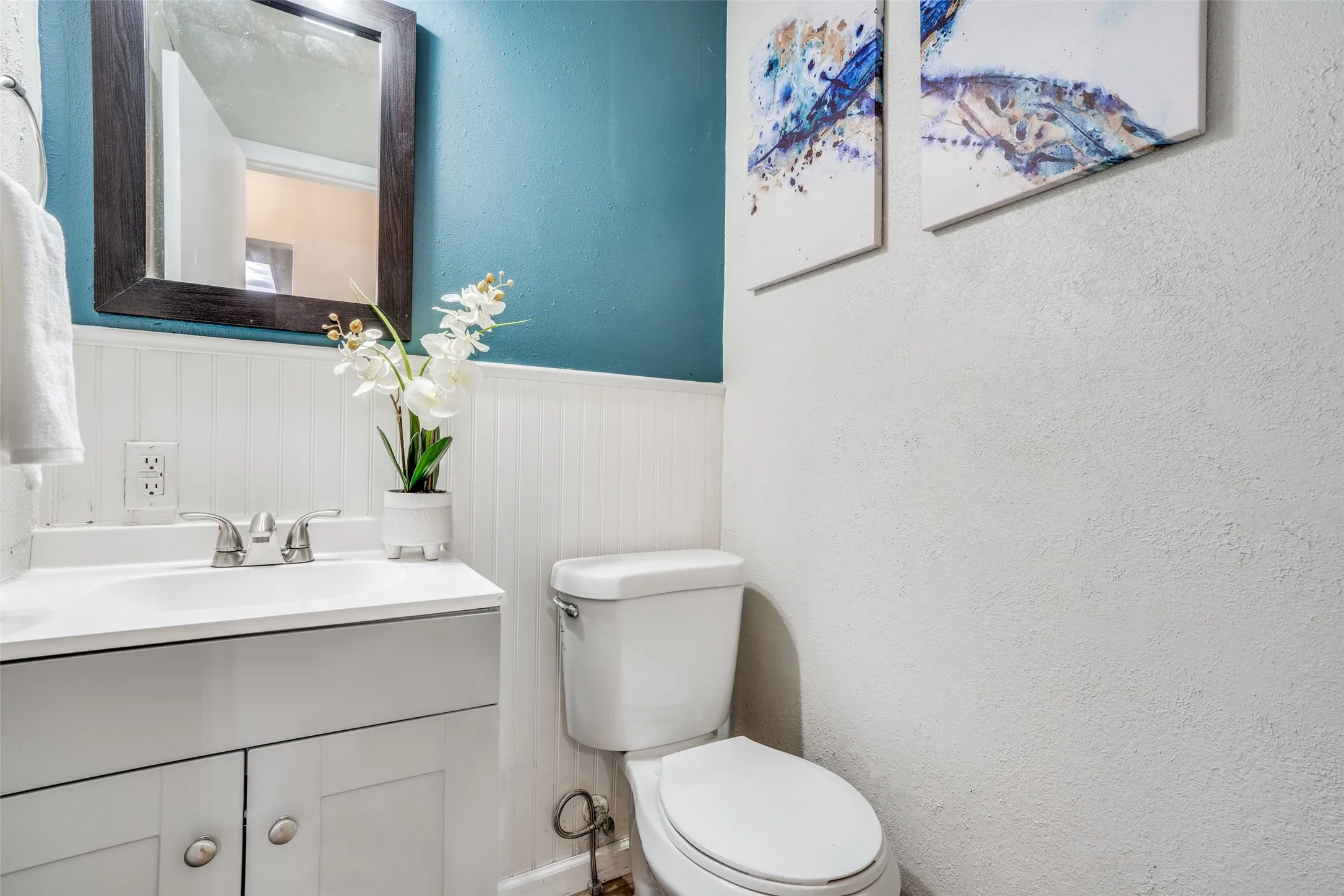 White vanity with integrated sink, chrome faucet, and dark wood-framed mirror