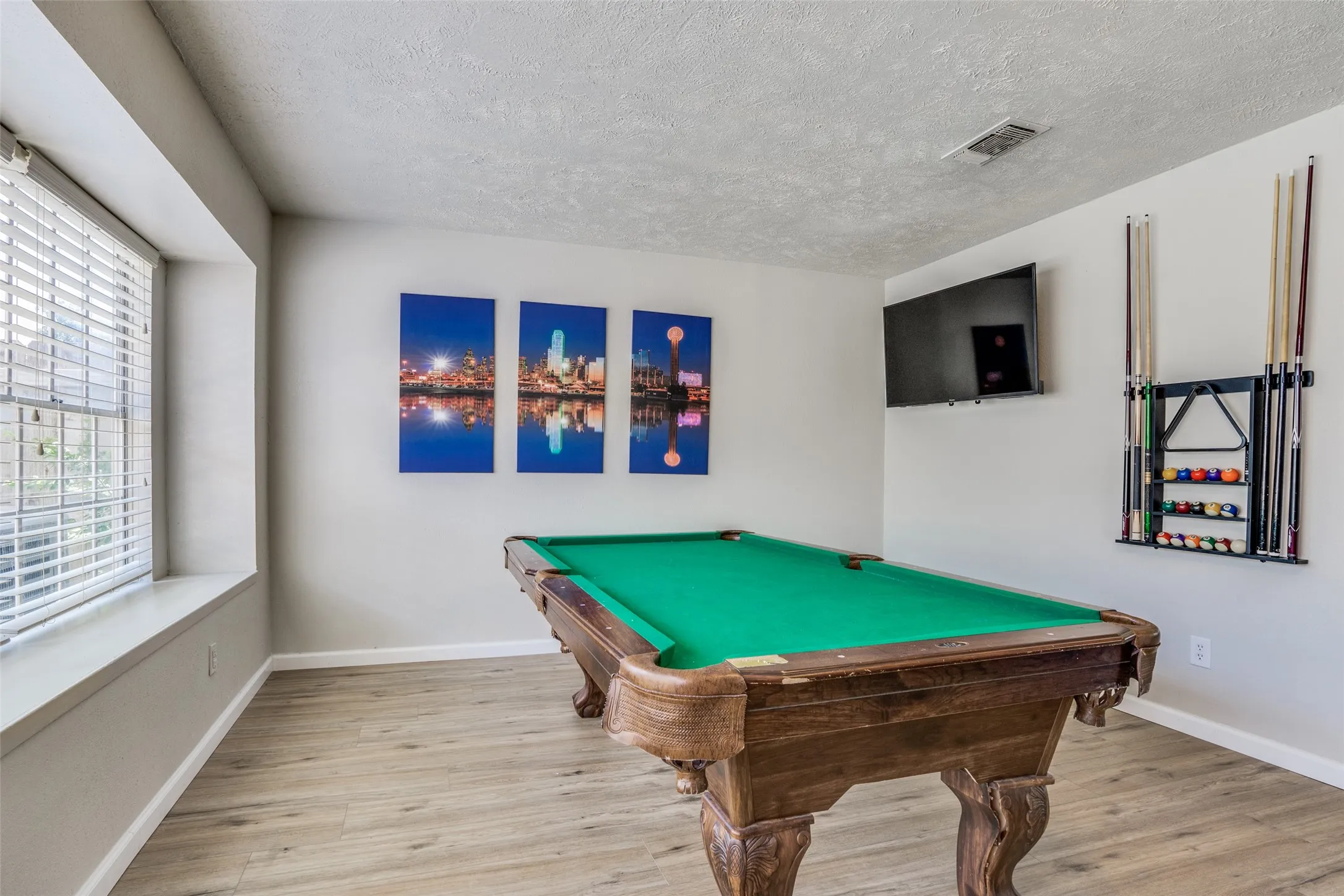 Recreation room featuring wood-finish flooring, a window with blinds, and a mounted television