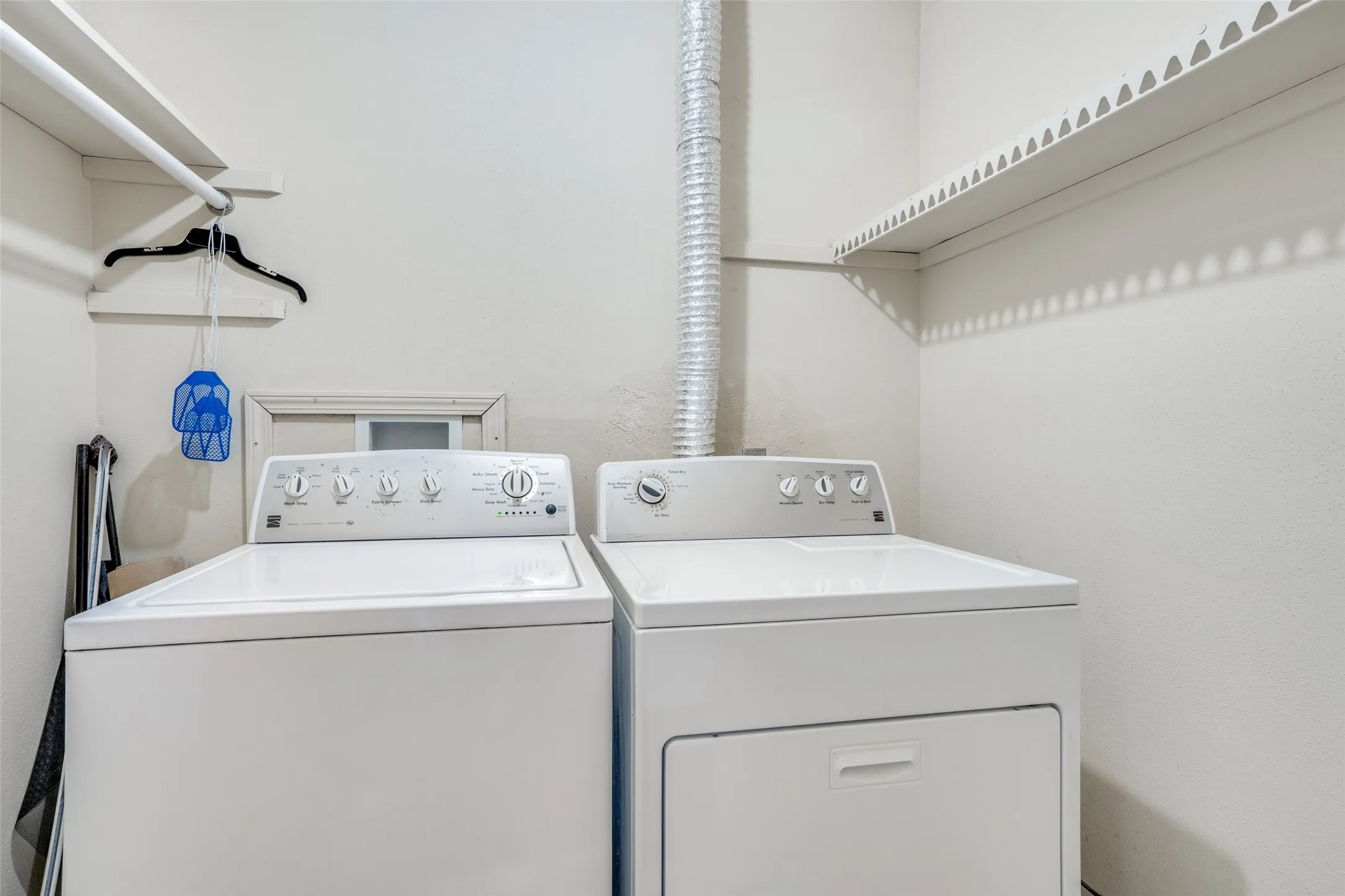 Laundry area with overhead shelving and a clothing rod