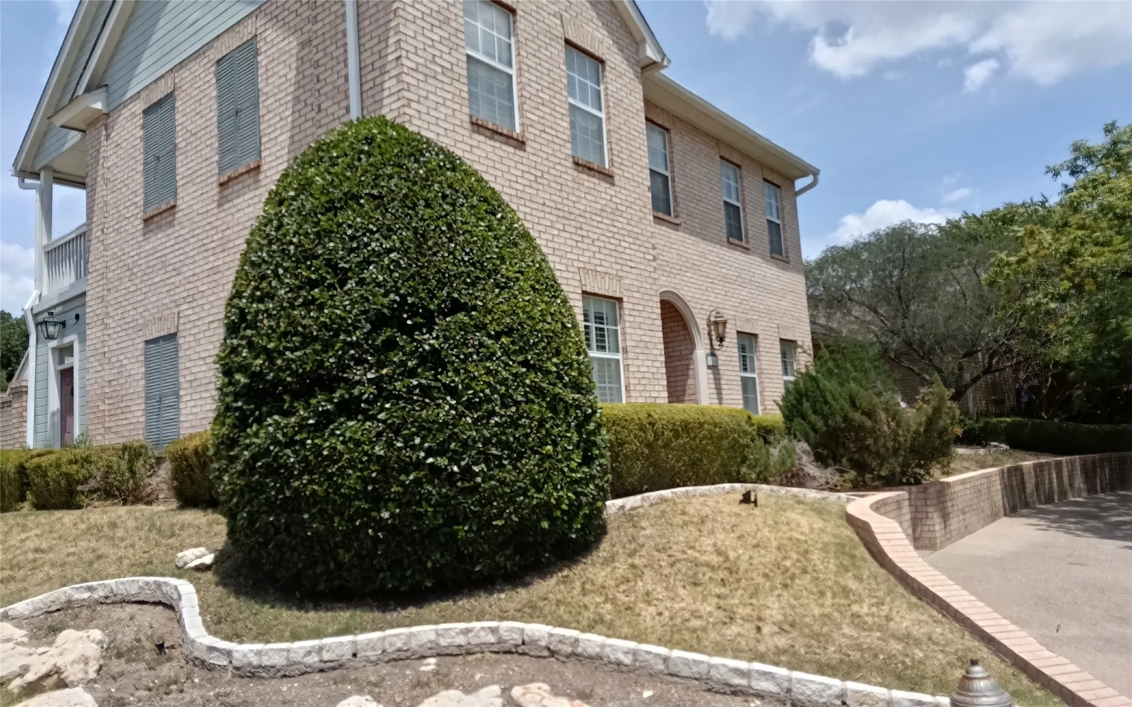 Brick exterior with multiple windows, arched entry, and a side balcony
