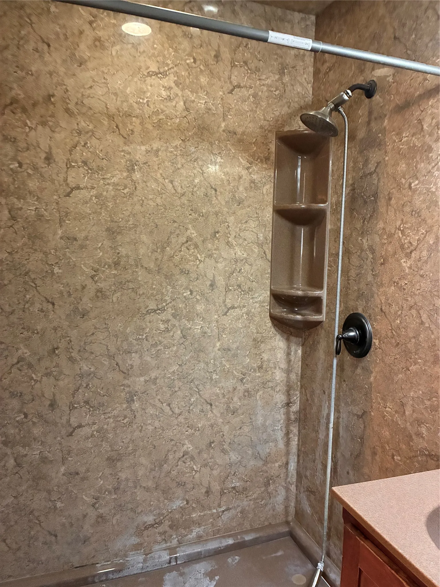 Shower enclosure with integrated shelving and a dark bronze shower fixture