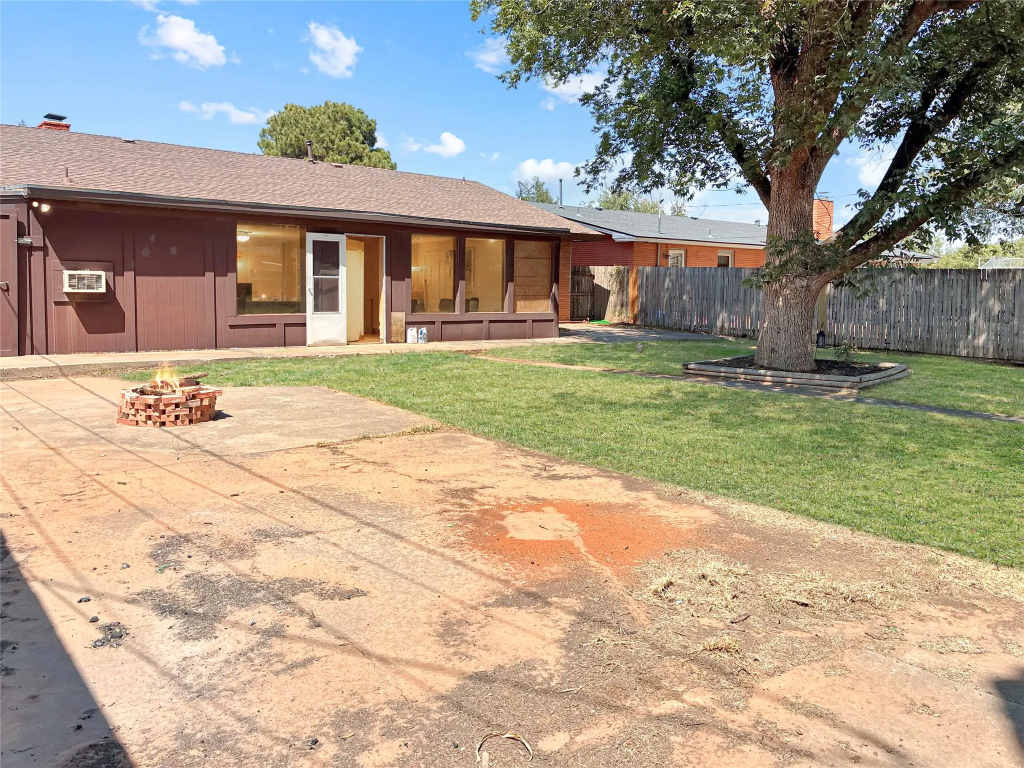 Expansive backyard featuring a large tree, a manicured lawn, and a concrete patio