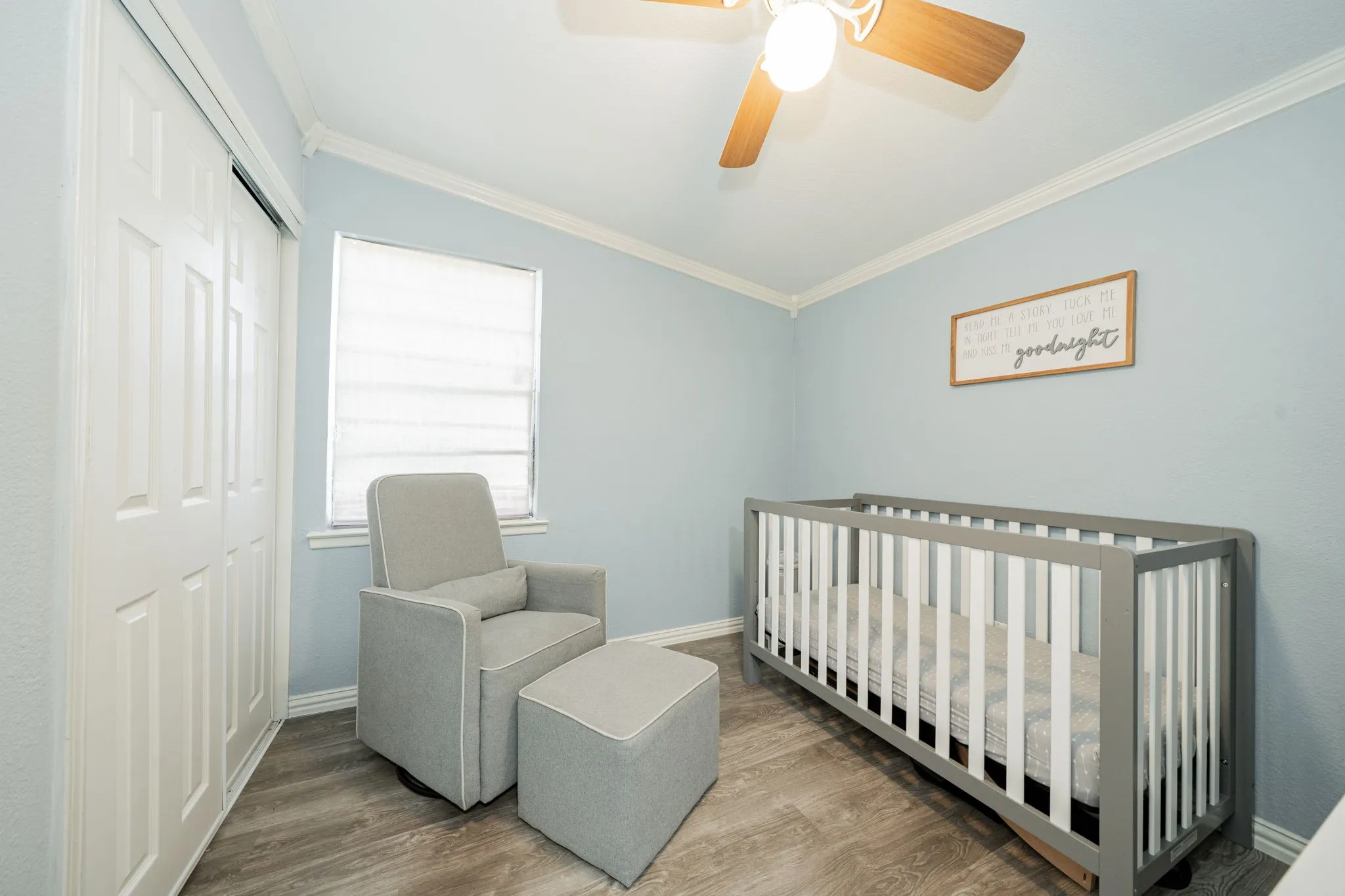 Bedroom with ornamental molding, wood finished floors, a closet, a crib, and a ceiling fan