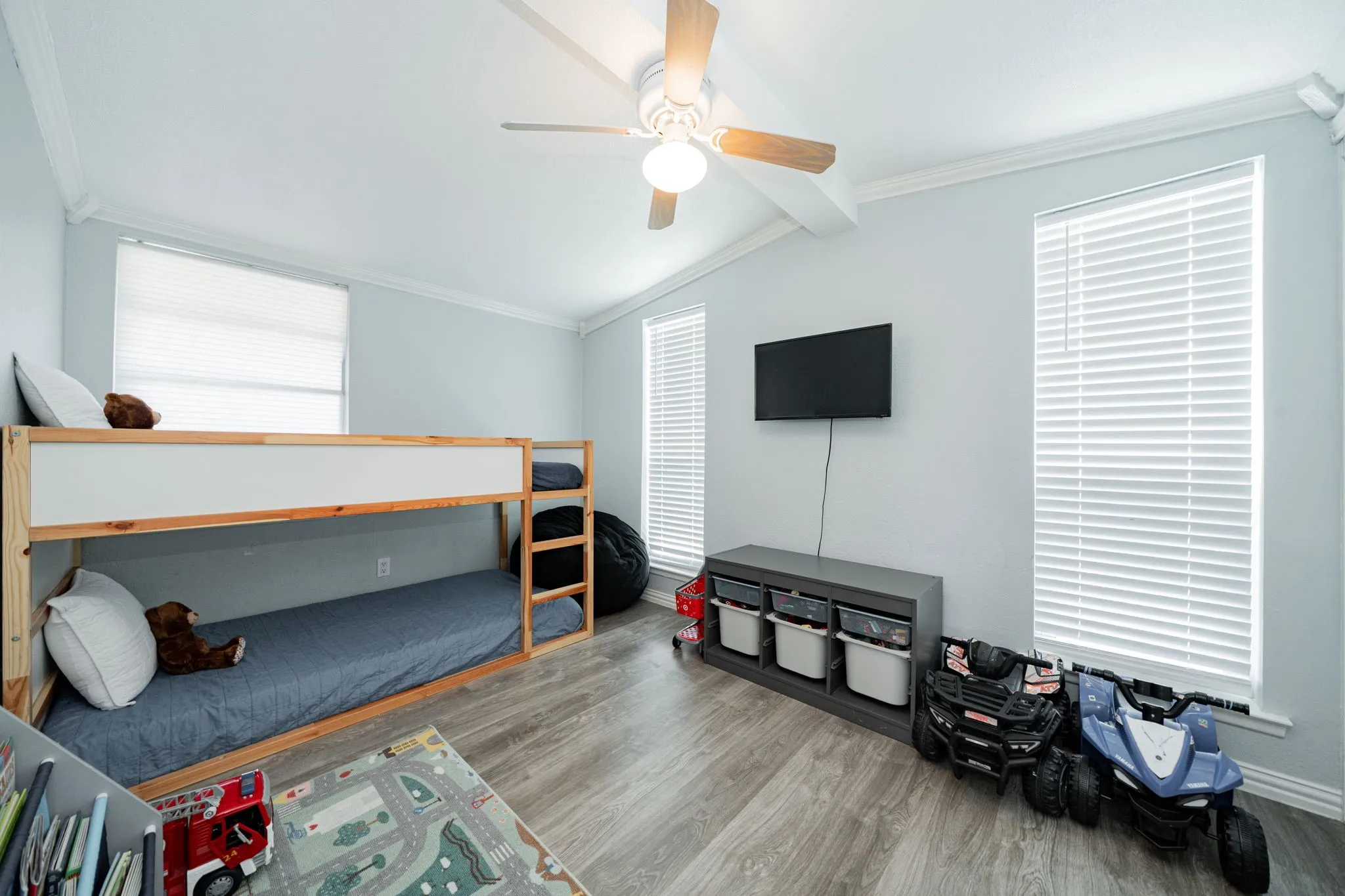 Bedroom with wood finished floors, multiple windows, ceiling fan, and crown molding
