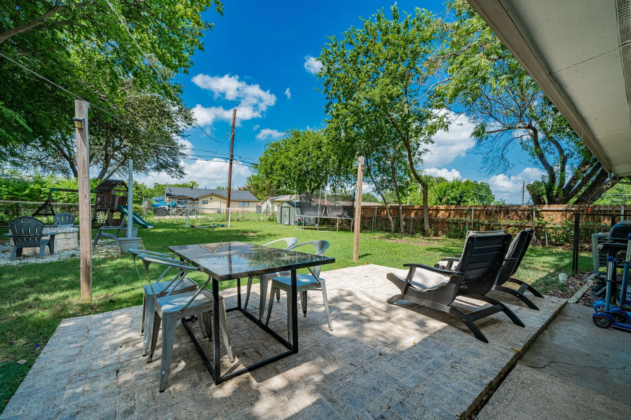 Fenced backyard featuring a trampoline, a patio area, outdoor dining space, and a playground