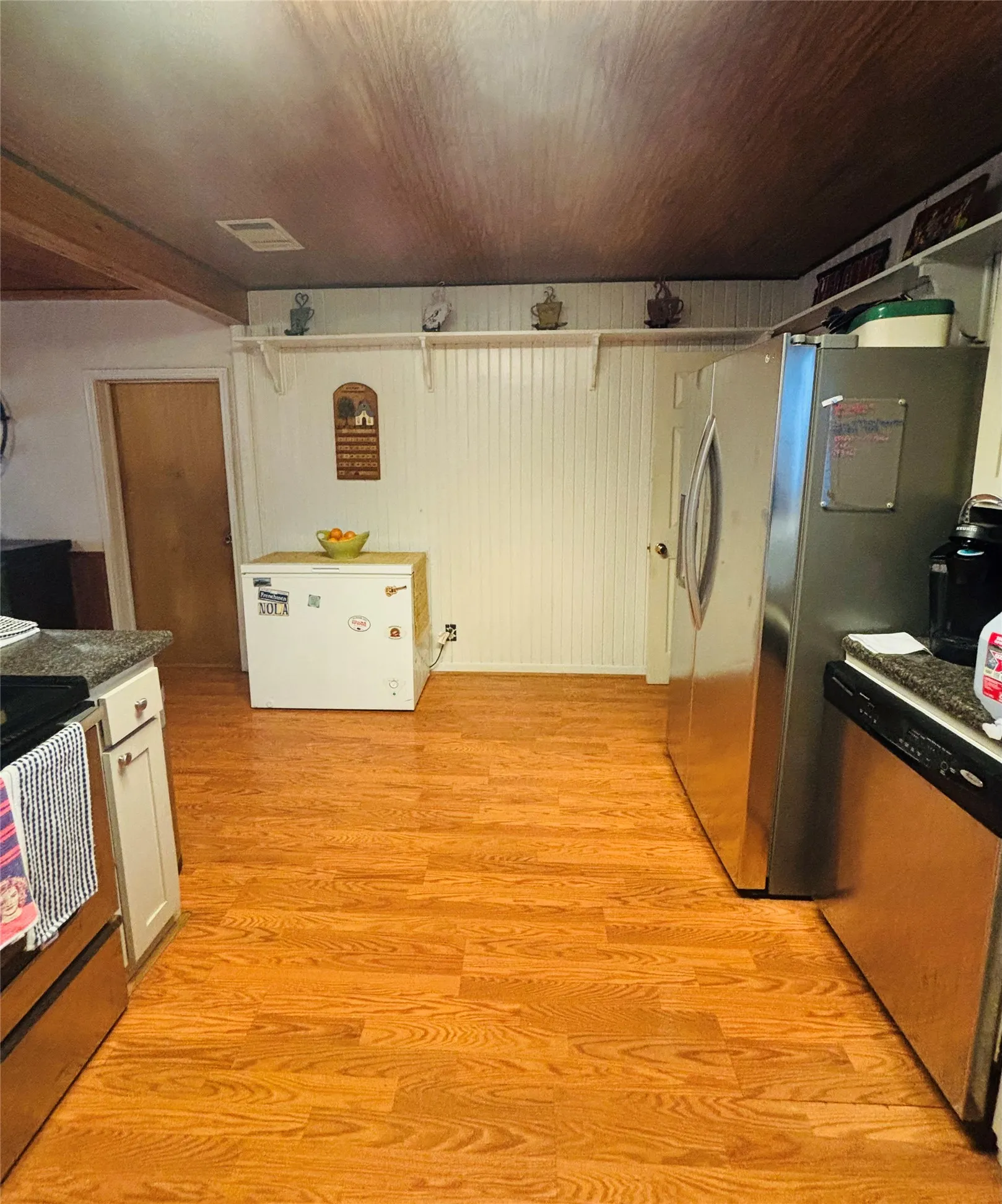 Wood-finish flooring with white beadboard wall paneling, stainless steel appliances, and a wood-finish ceiling