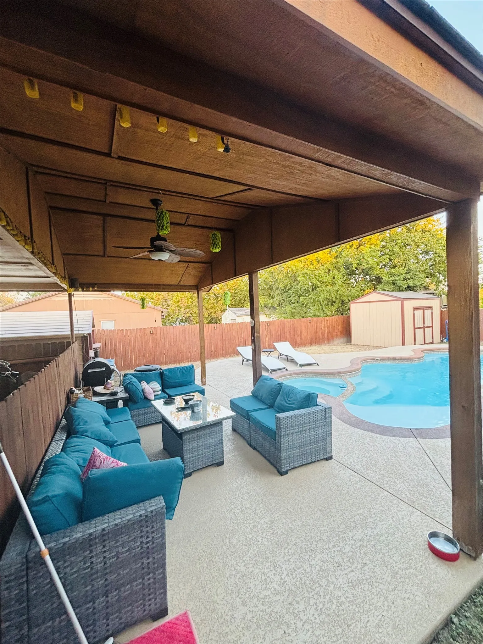 Covered patio with textured concrete flooring, a ceiling fan, and string lighting