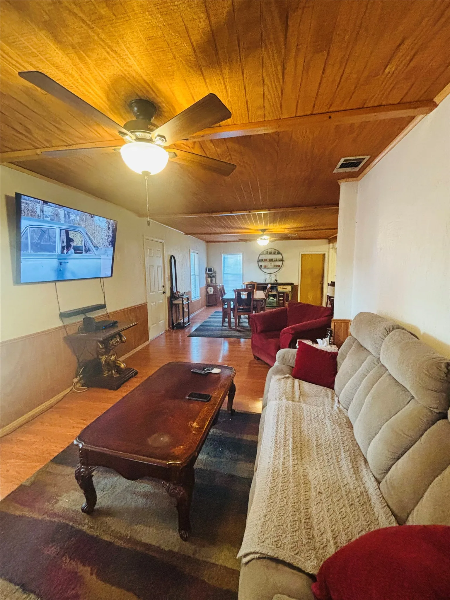 Wood-finish ceiling, wood-finish flooring, half-wall paneling, ceiling fan with integrated lighting